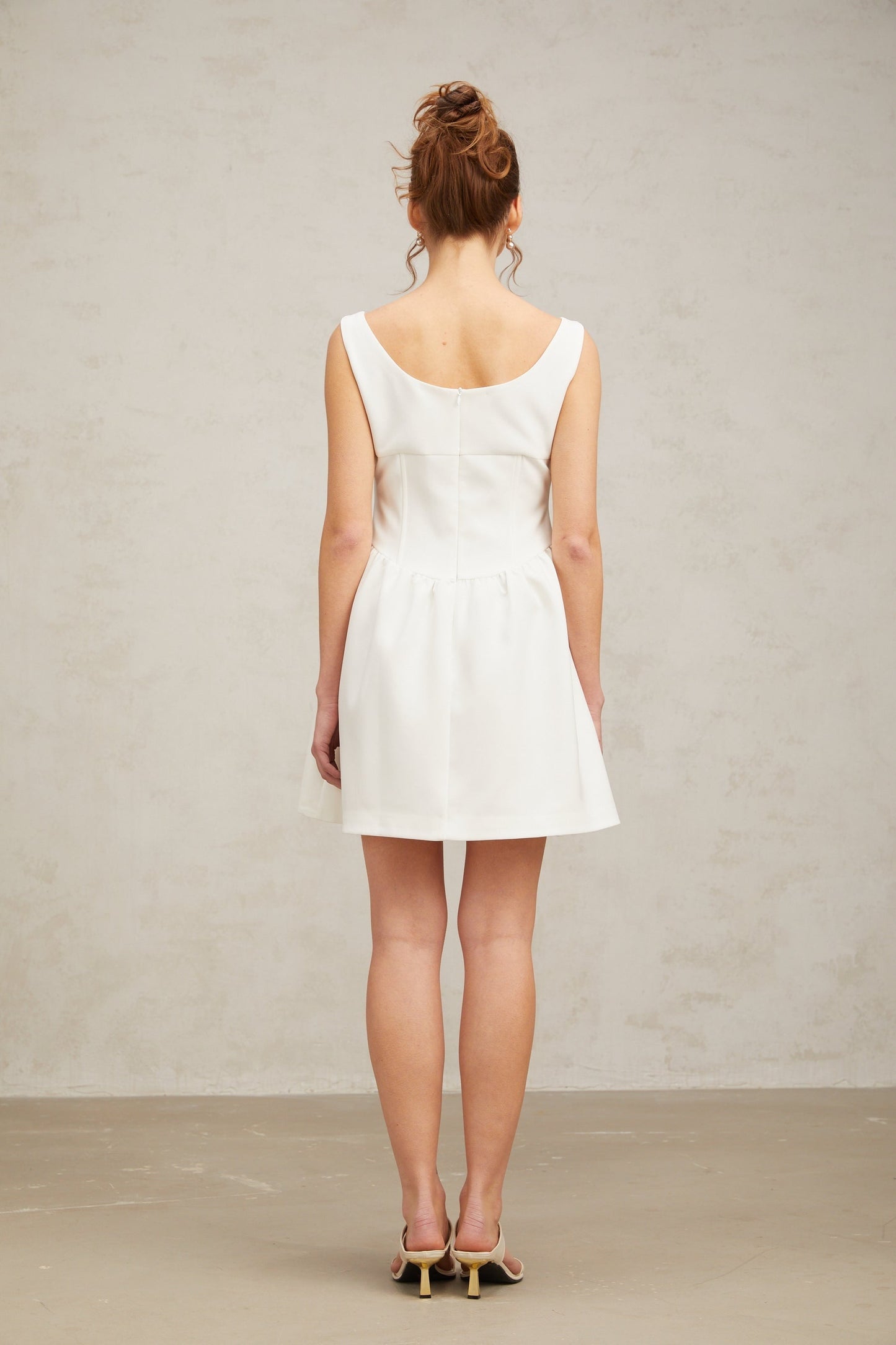 A short white mini dress adorned with crystal embellishments featuring a fitted silhouette and shimmering details