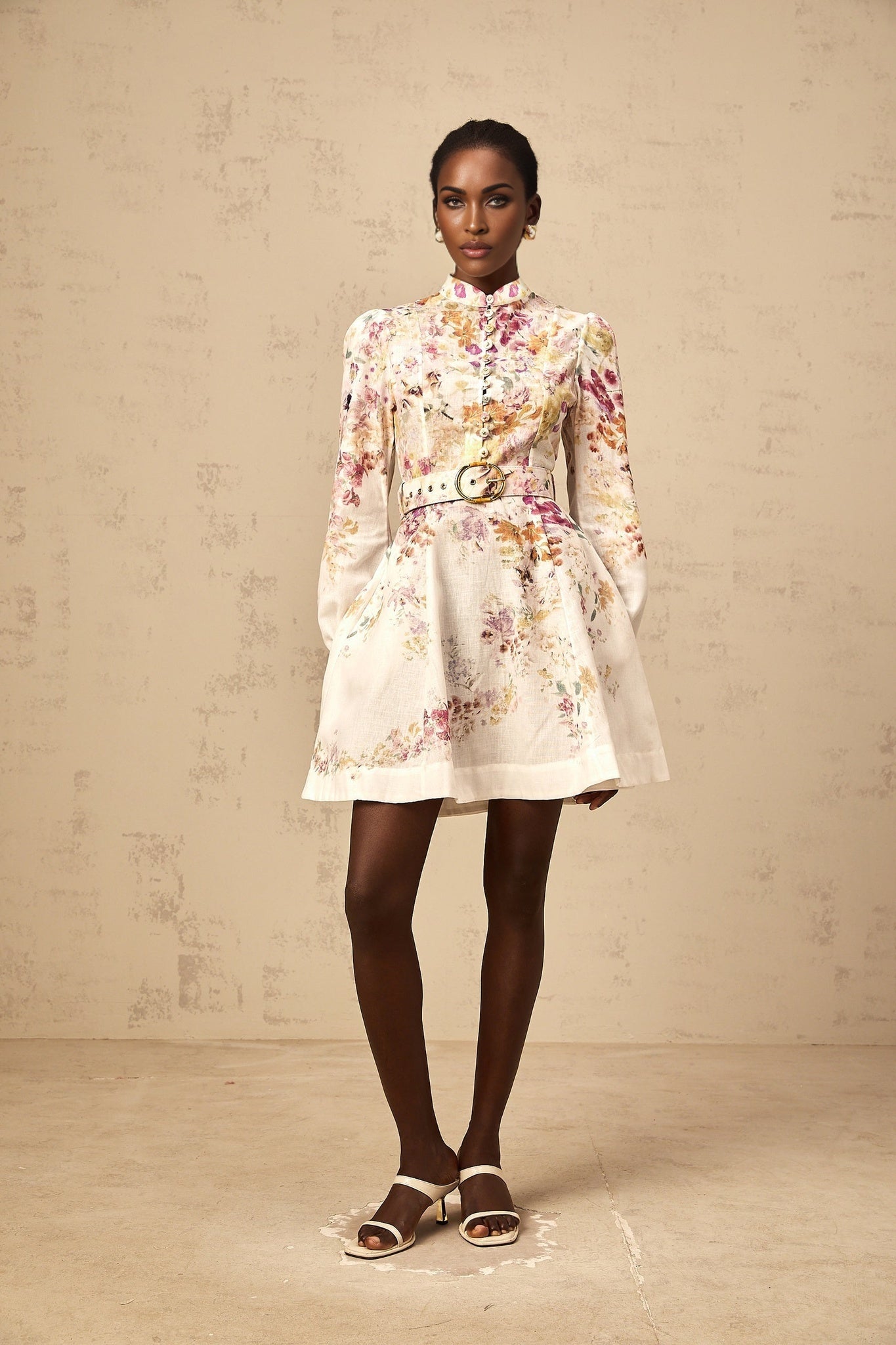 A short white mini dress with a colorful floral print pattern covering the fabric featuring a fitted bodice and flared skirt