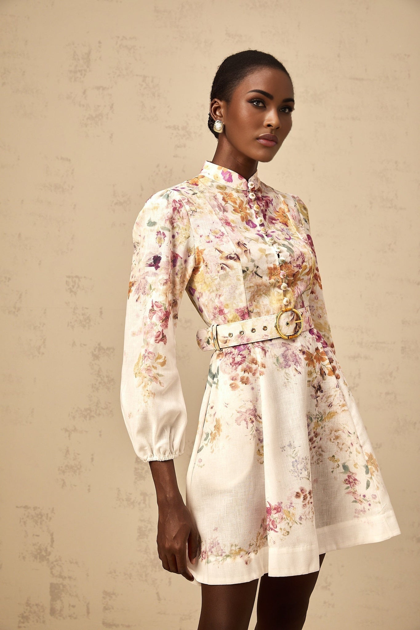 A short white mini dress with a colorful floral print pattern covering the fabric featuring a fitted bodice and flared skirt