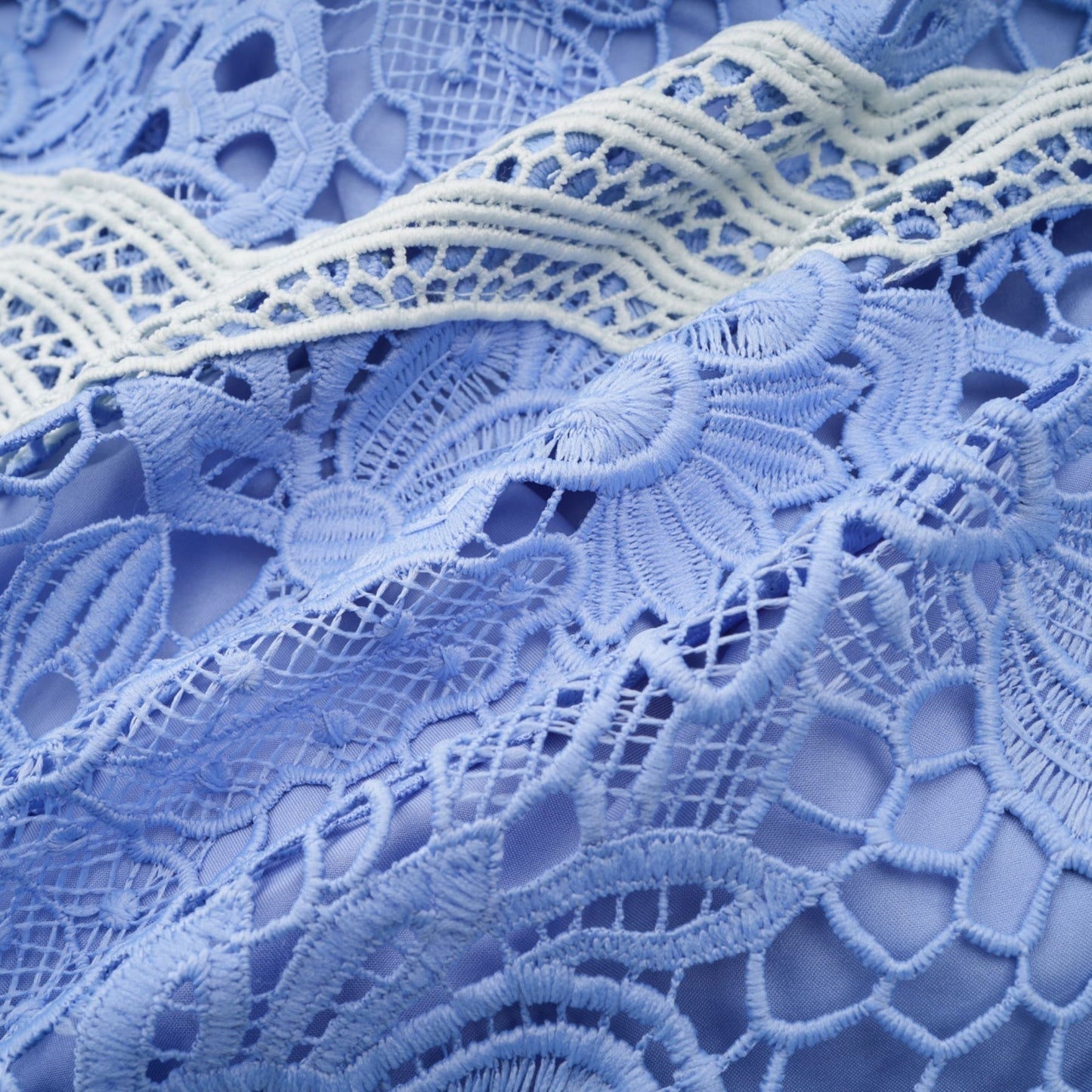 A short white mini dress with a Vneck and colorful floral embroidery detail worn by a model standing against a plain background