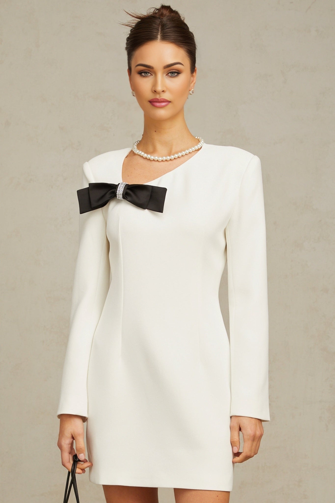 A short white mini dress with an asymmetric hemline featuring a large bowknot detail on one side