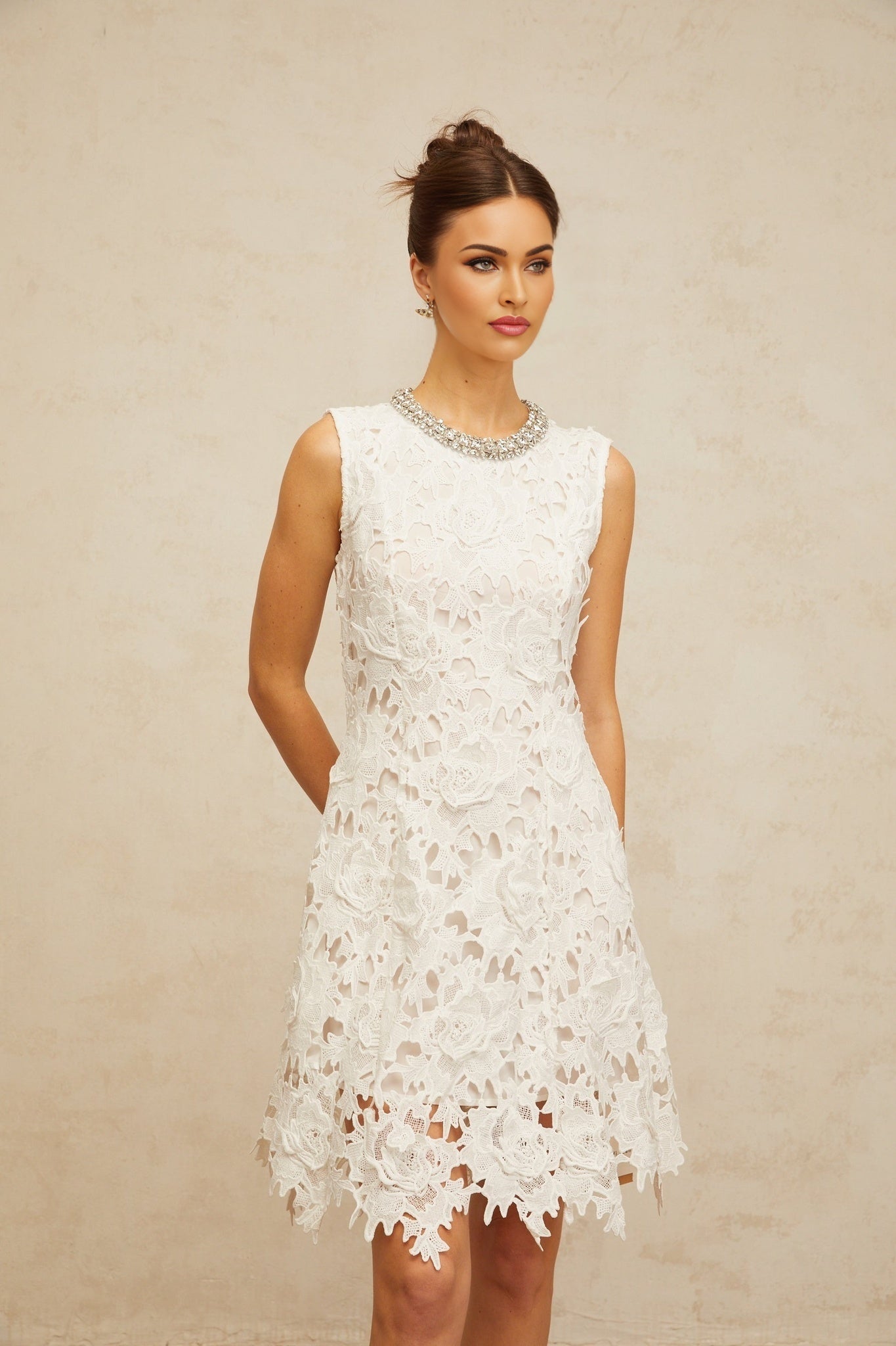 A short white mini dress with embellished corded lace details featuring intricate patterns and a delicate feminine design