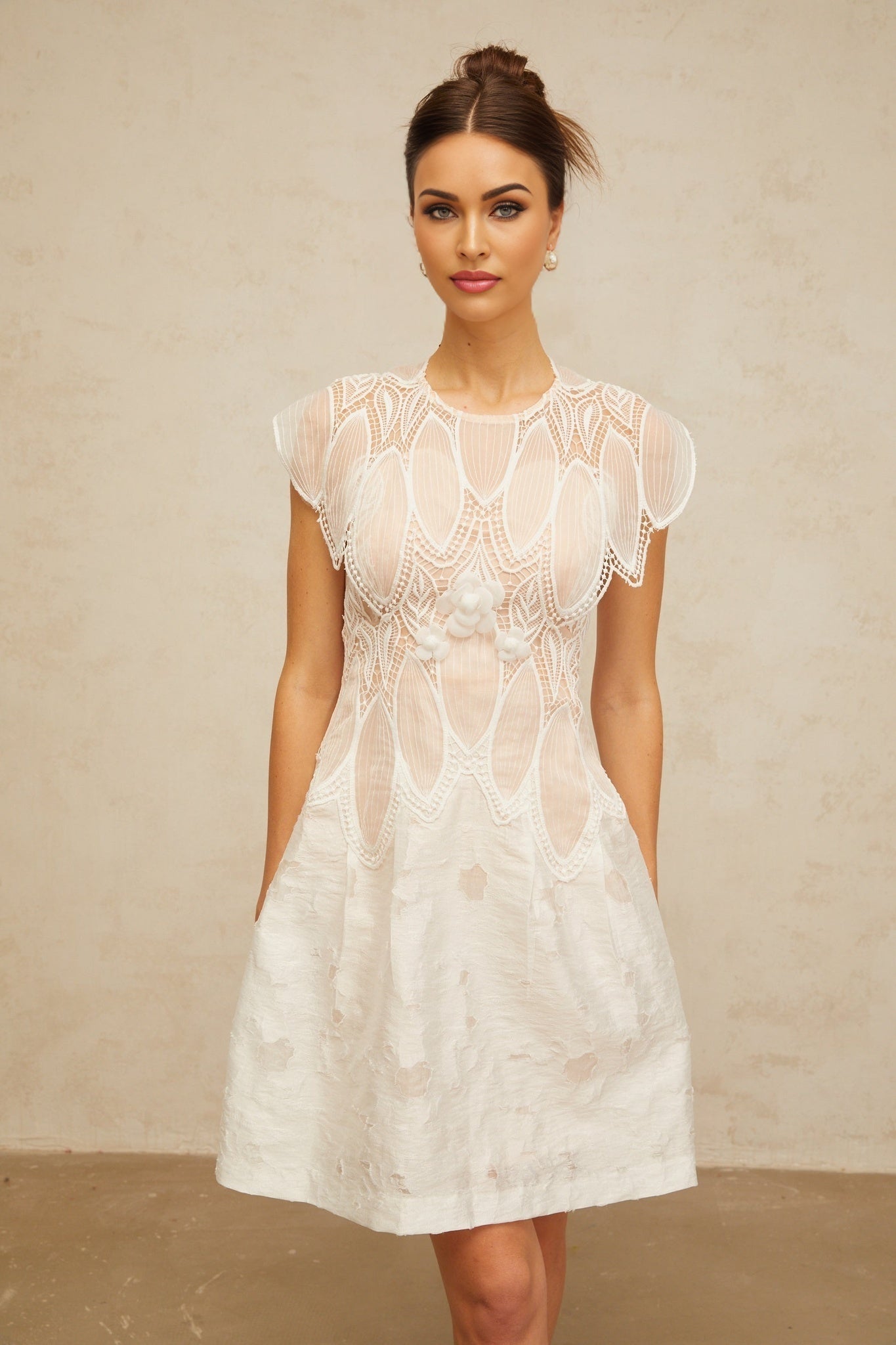 A short white mini dress with intricate 3D floral lace details featuring corded petals covering the bodice and skirt