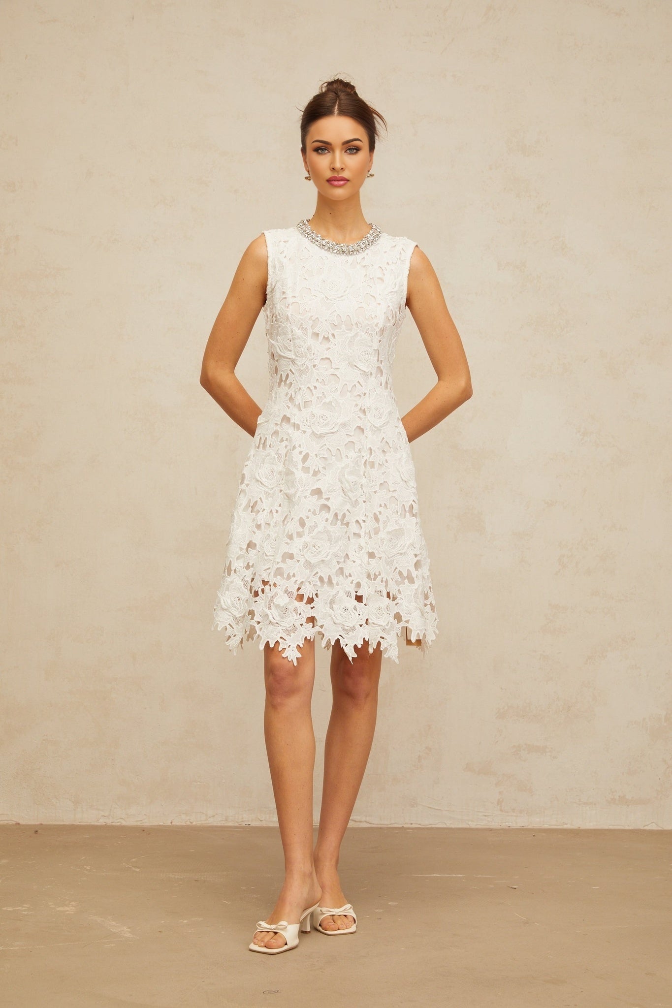A short white mini dress with intricate embellished corded lace details featuring a delicate floral pattern