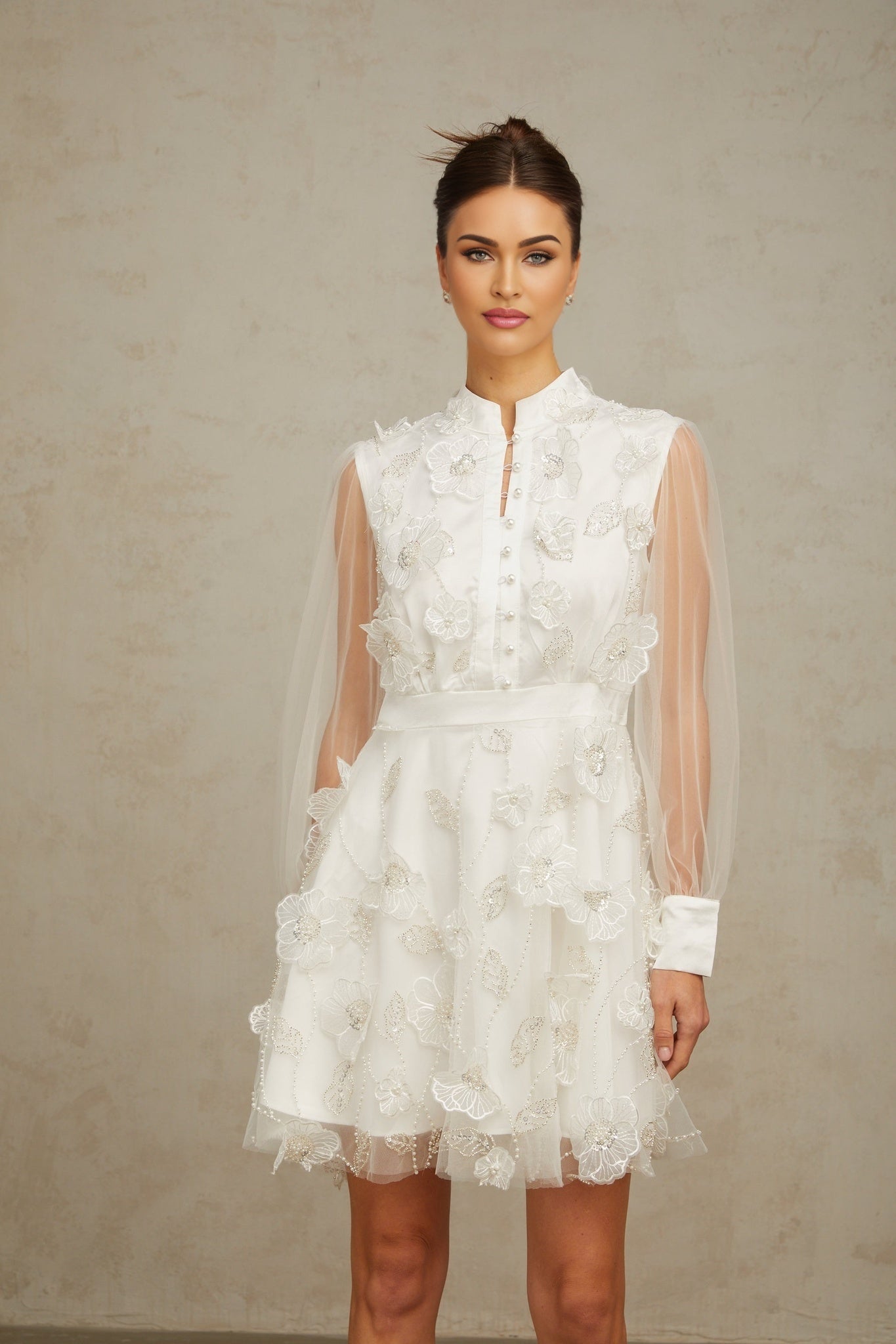 A short white mini dress with threedimensional floral tulle petals covering the bodice and skirt creating a textured and romantic look