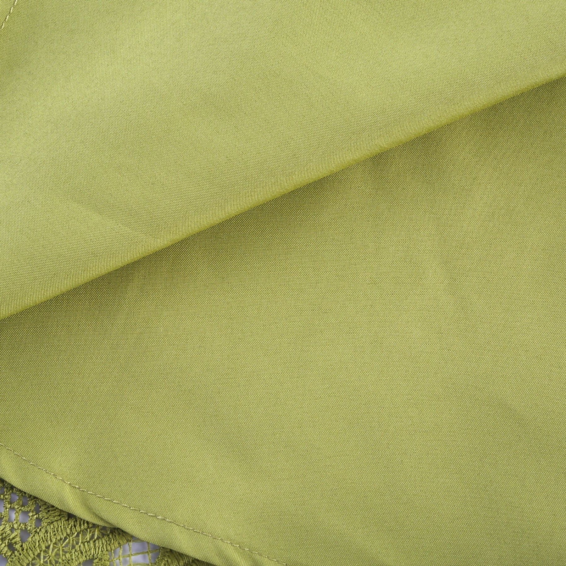 A short white minidress with embroidery details and cut out sections worn by a model against a plain background