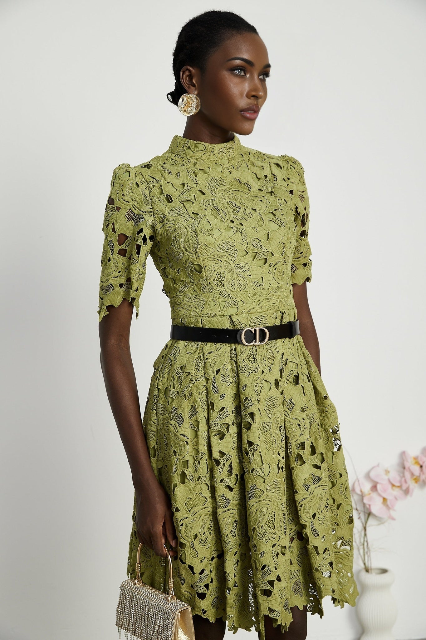 A short white minidress with embroidery details and cutout sections worn by a model