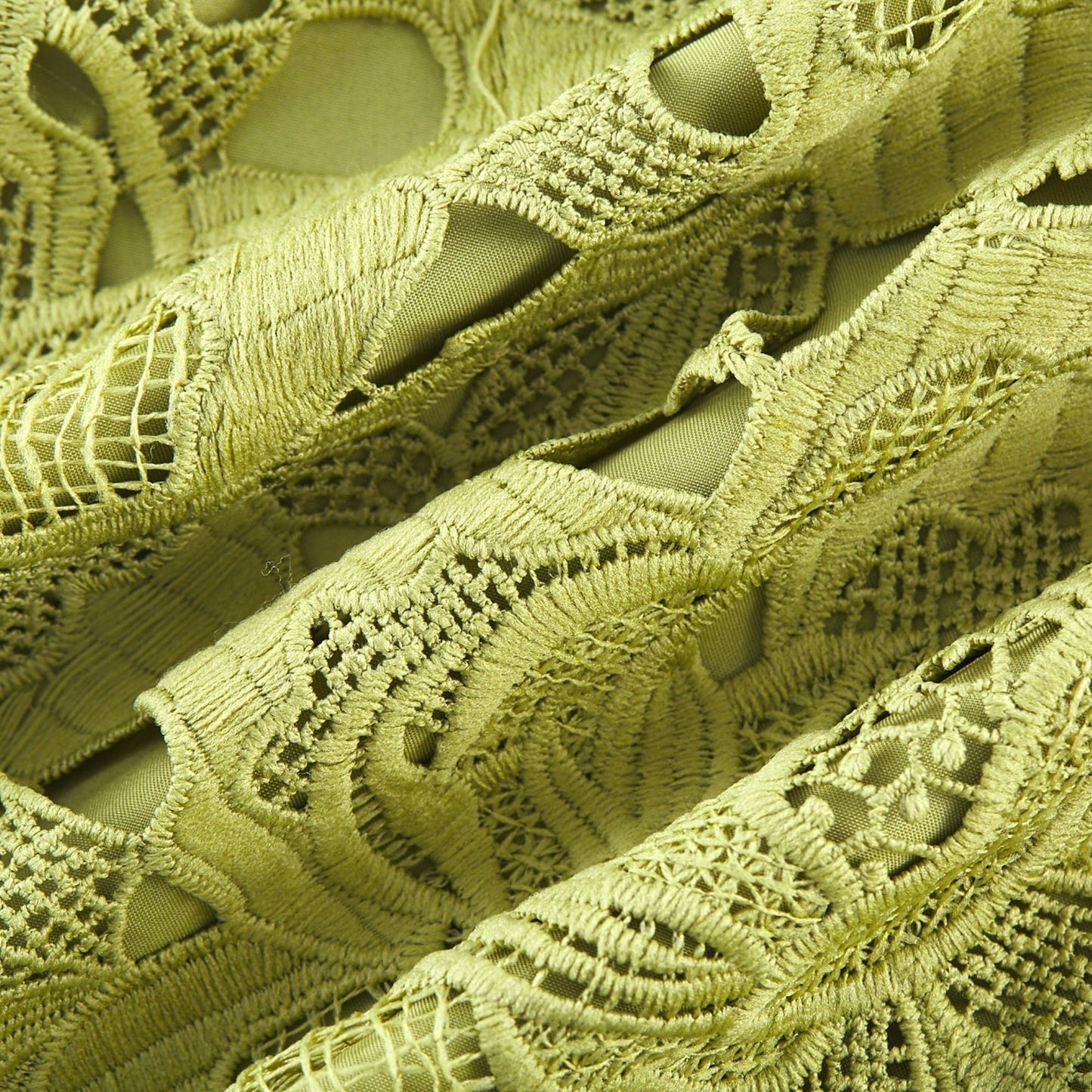 A short white minidress with embroidery details and cutout sections worn by a model