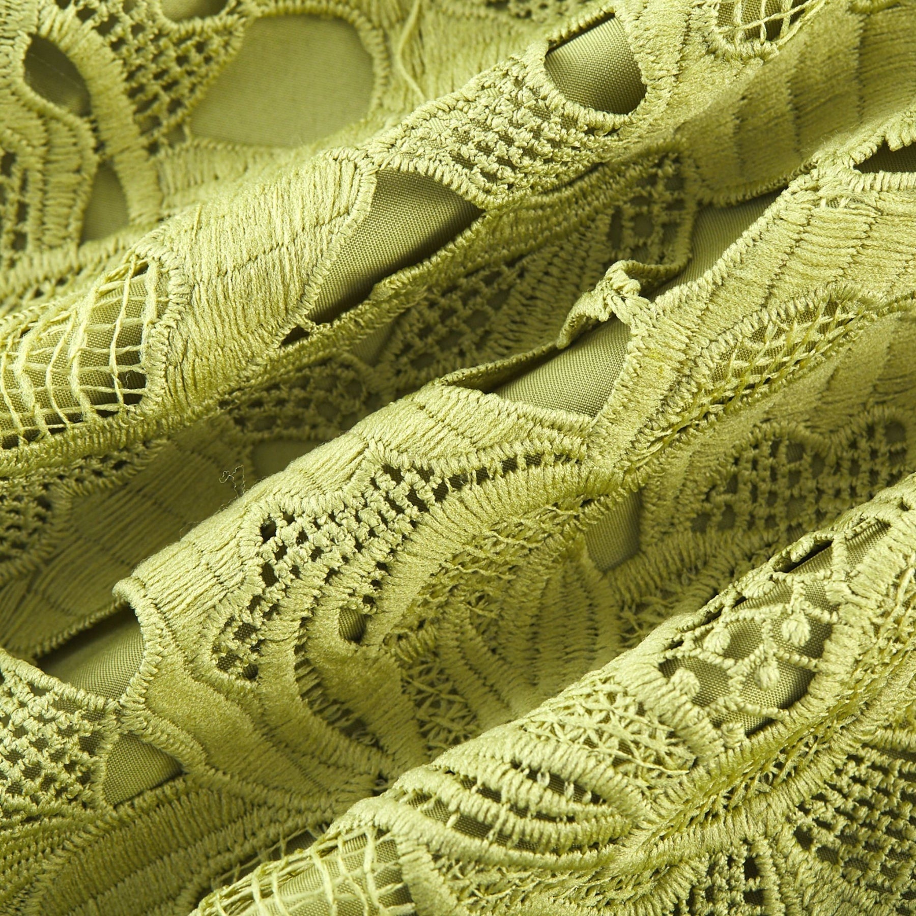 A short white minidress with embroidery details and cutout sections worn by a model