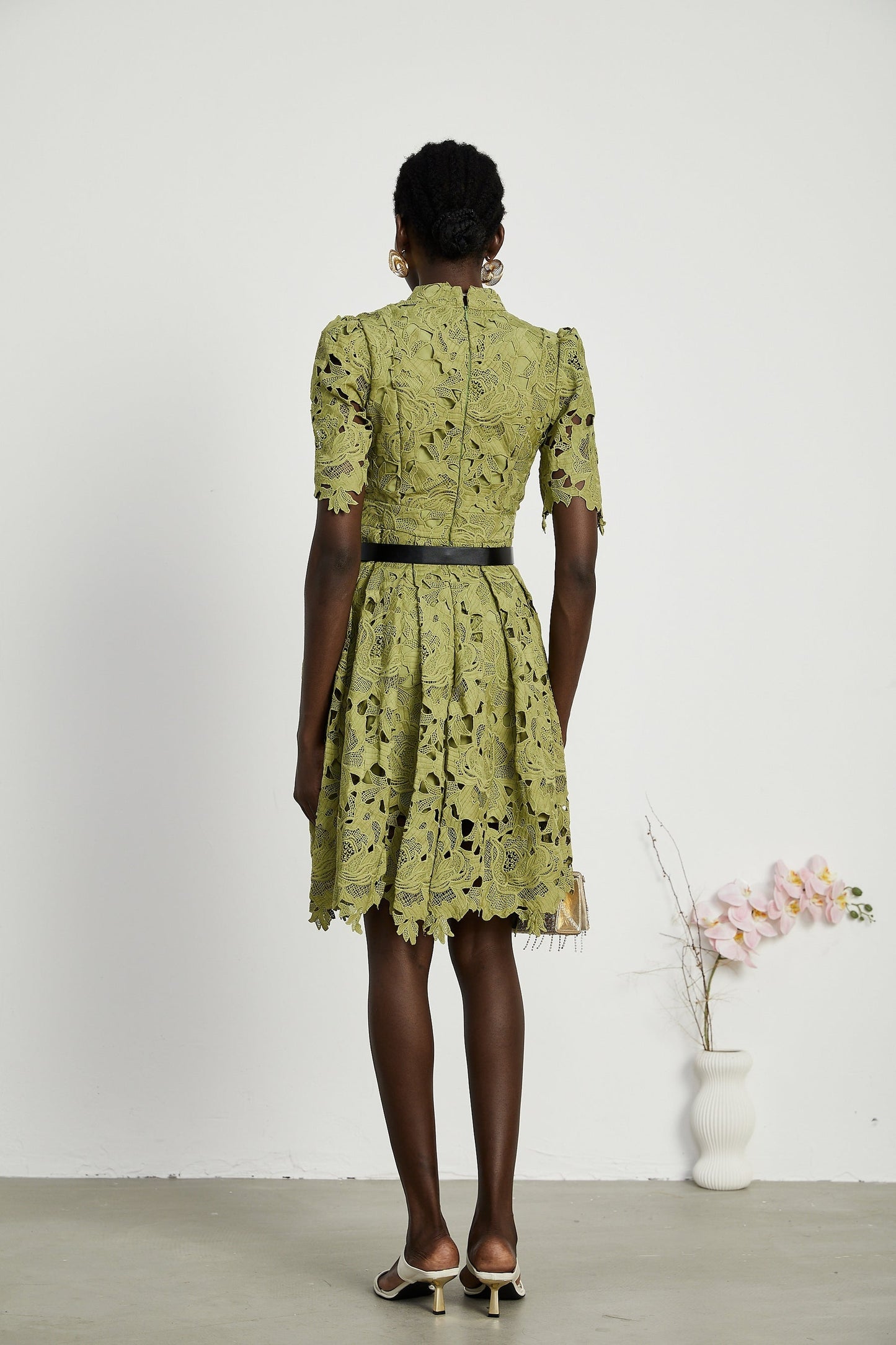 A short white minidress with embroidery details and cutout sections worn by a model