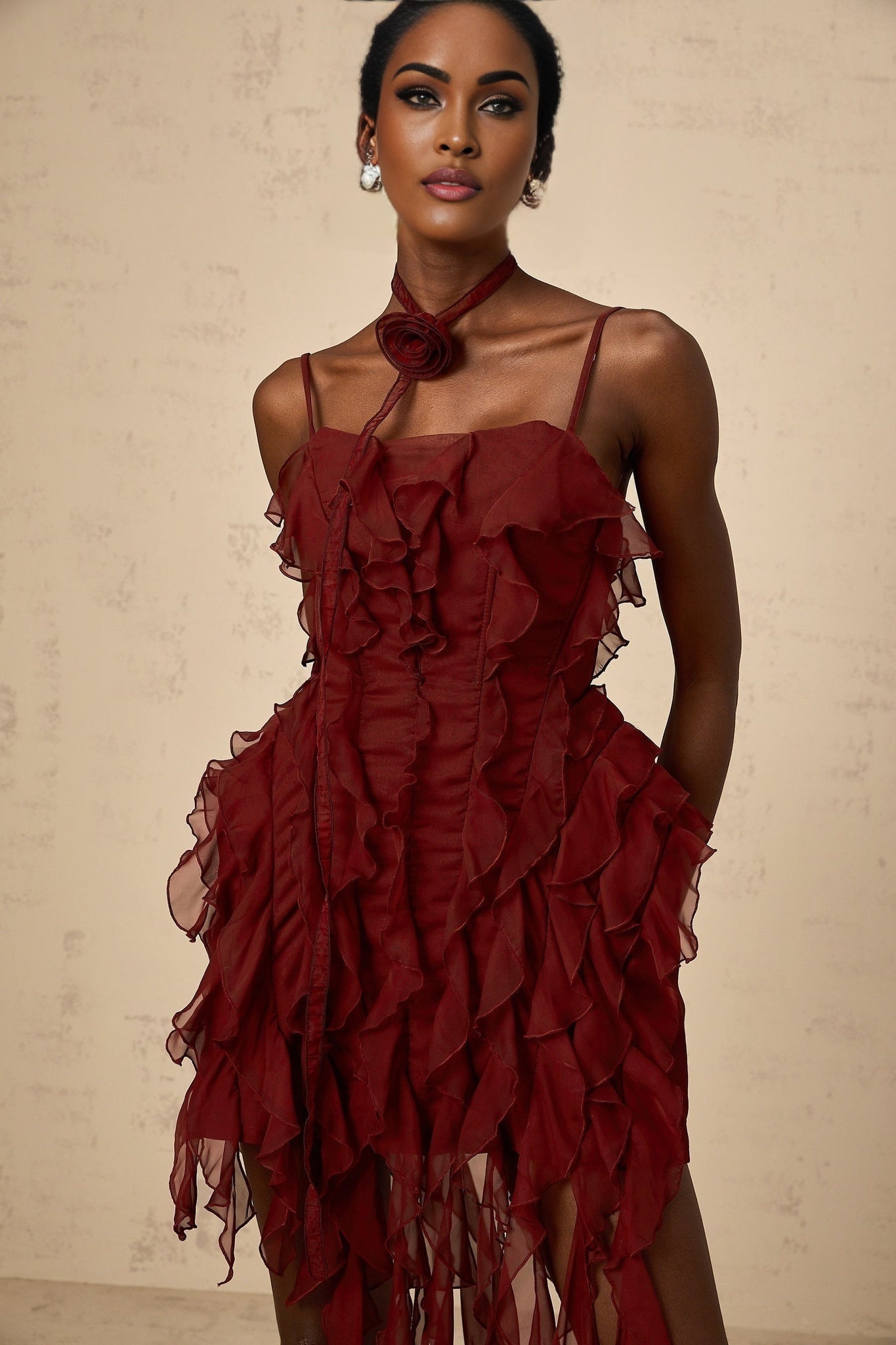 A short winered mini dress with ruffled details and rose appliques adorning the fabric