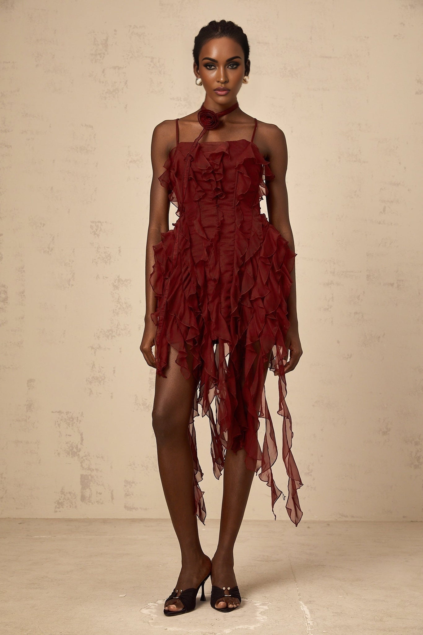A short winered mini dress with ruffles and rose appliques adorning the fabric