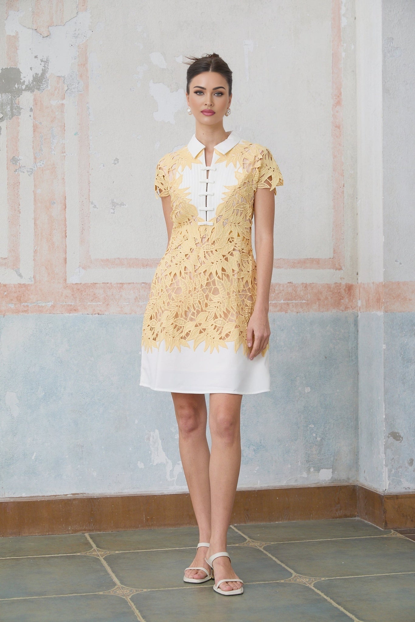 A short yellow mini dress with decorative leaf appliques adorning the fabric