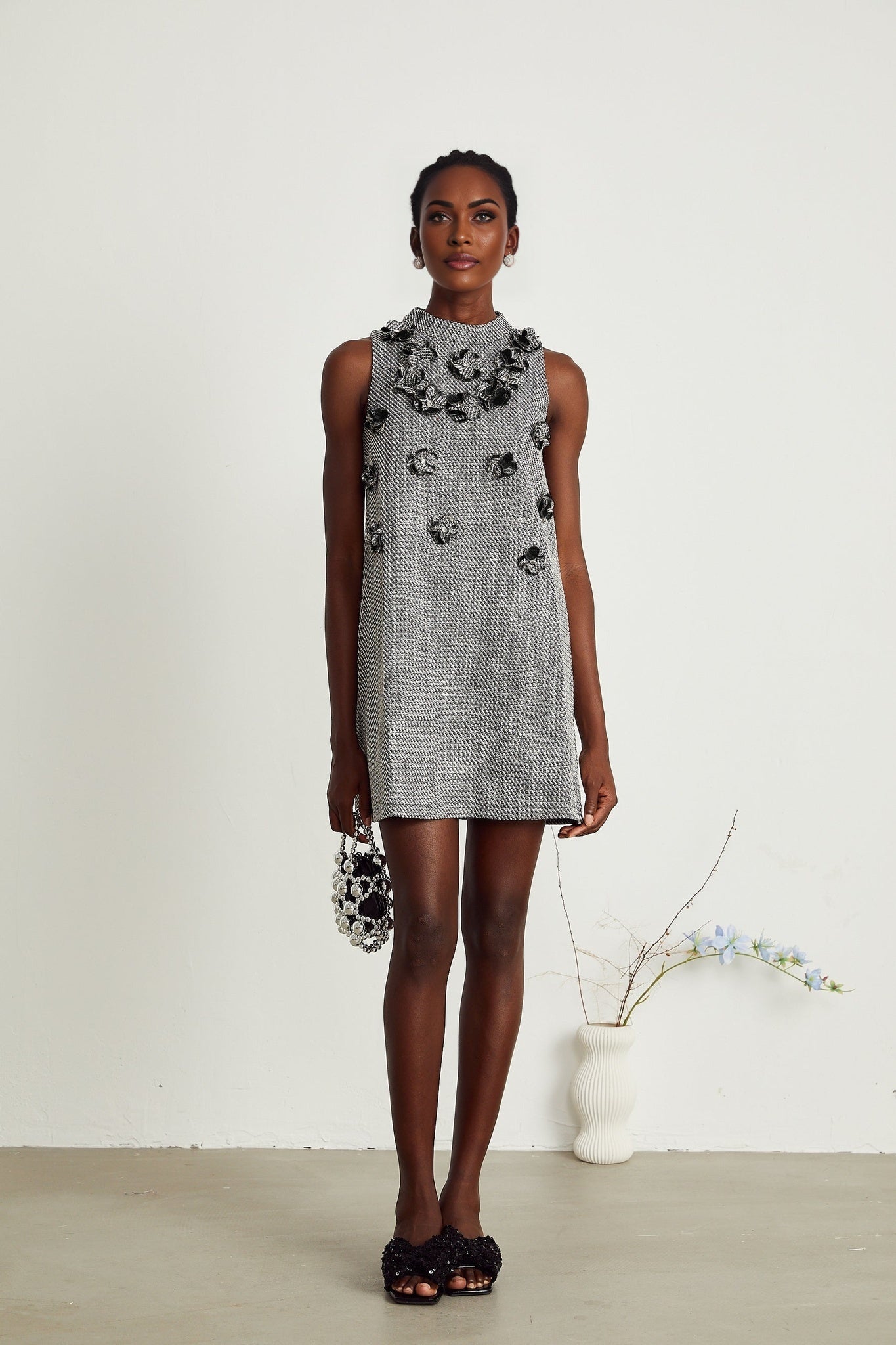 A sleeveless mini dress with faux flower embellishments featuring a floral pattern and likely in pastel or vibrant colors suitable for spring or summer occasions
