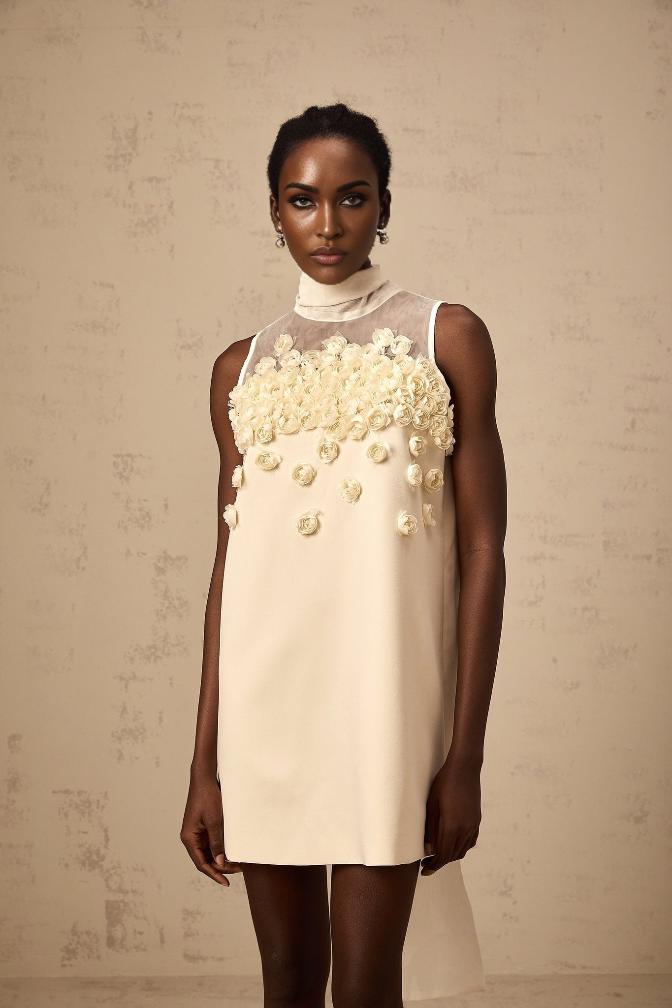 A sleeveless mini dress with faux flowers adorning the fabric in a vibrant floral pattern