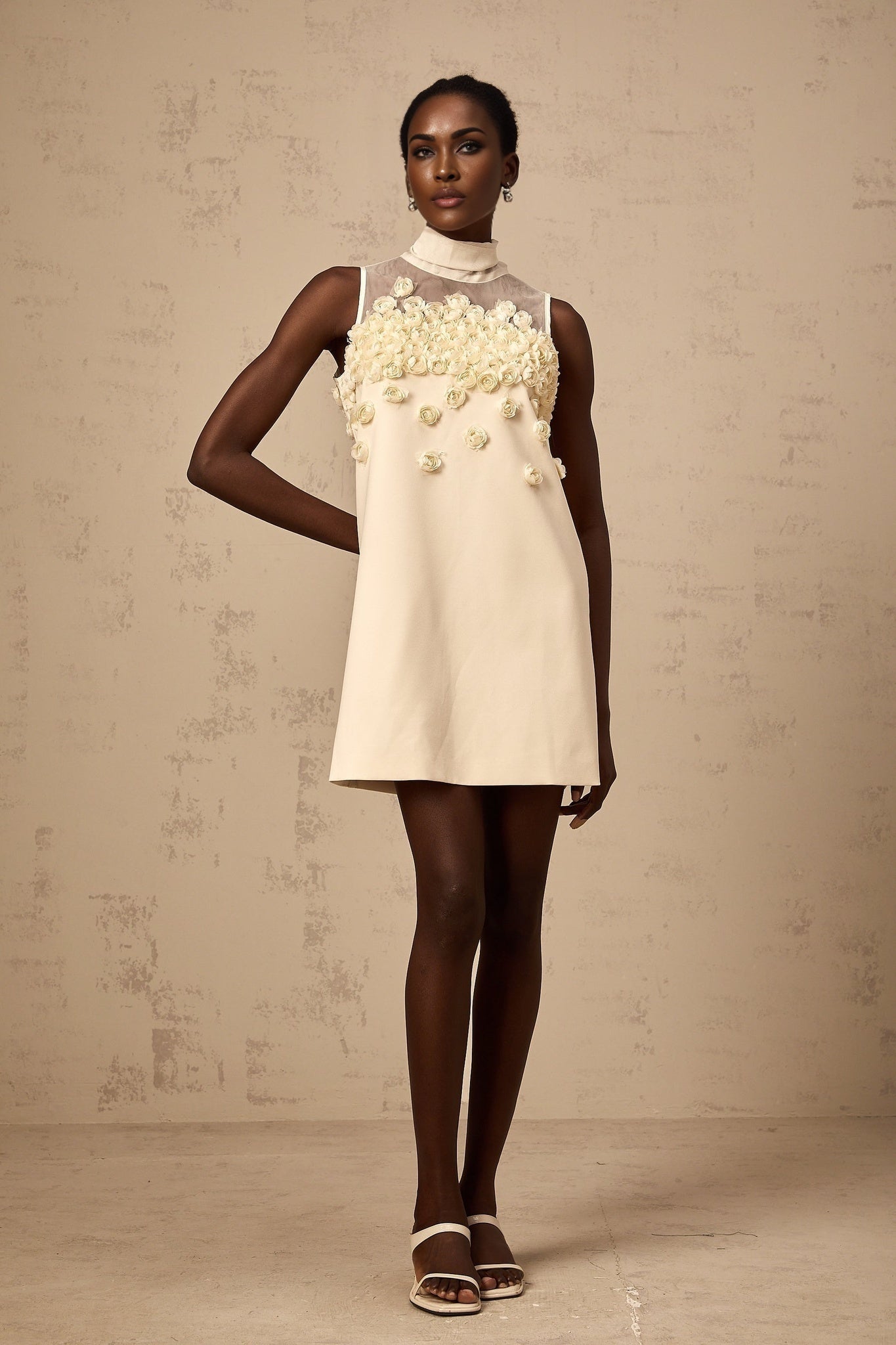 A sleeveless mini dress with floral pattern featuring faux flowers on a light background
