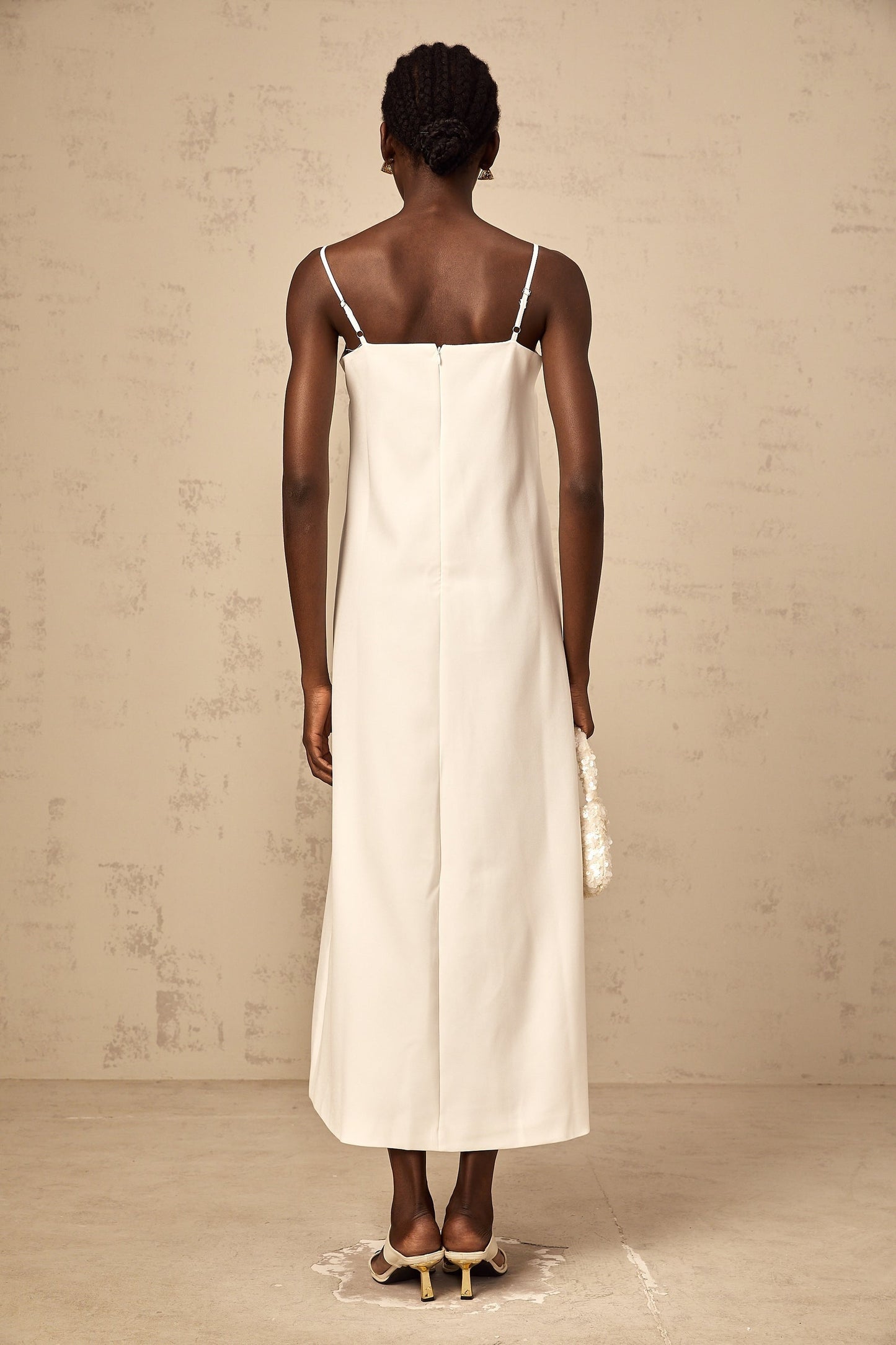 A sleeveless white midi dress with 3D petal details featuring a floral inspired texture and a feminine silhouette