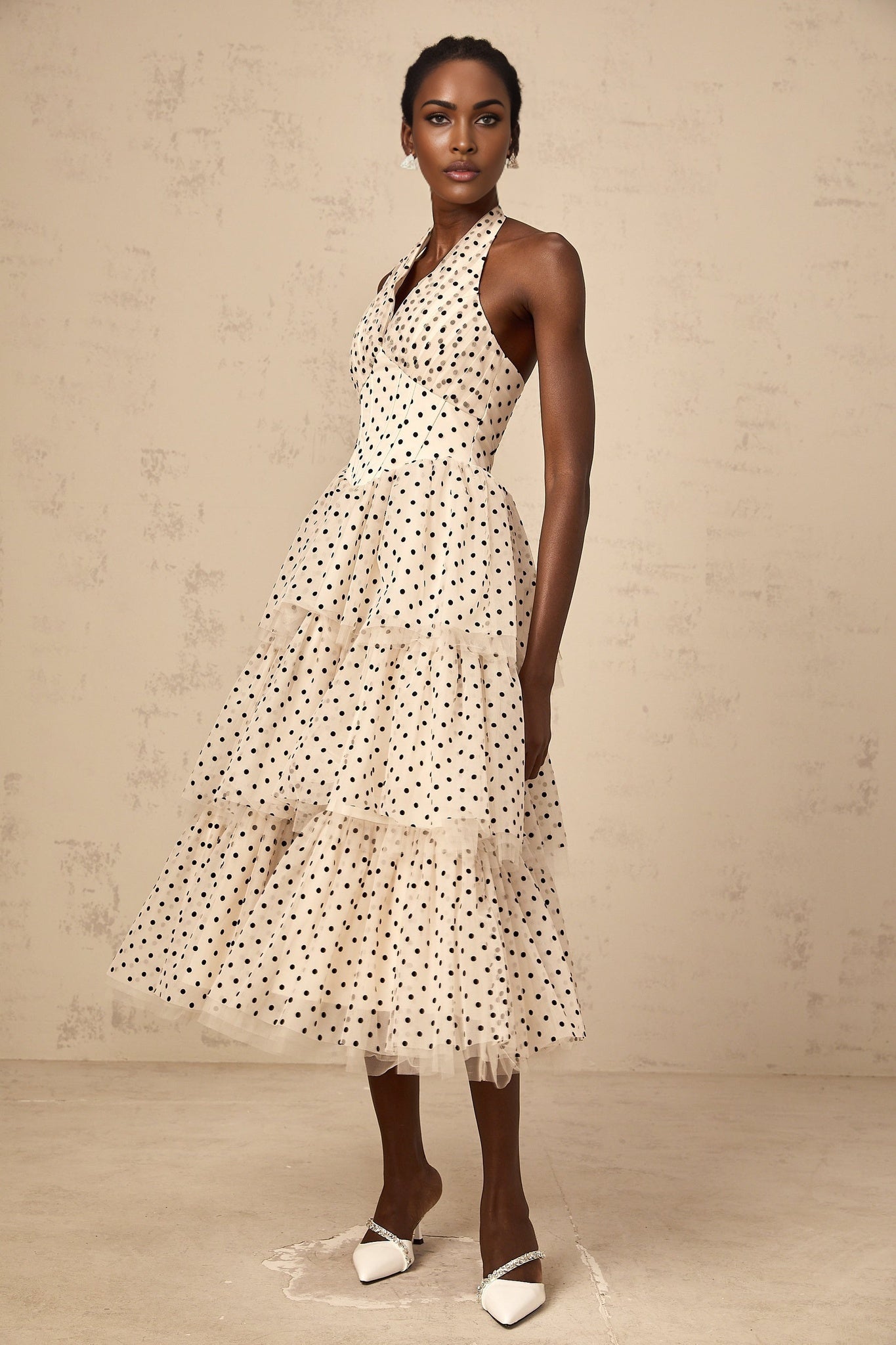 A tiered midi dress in ivory color with polka dot pattern featuring multiple layers and a midlength hemline