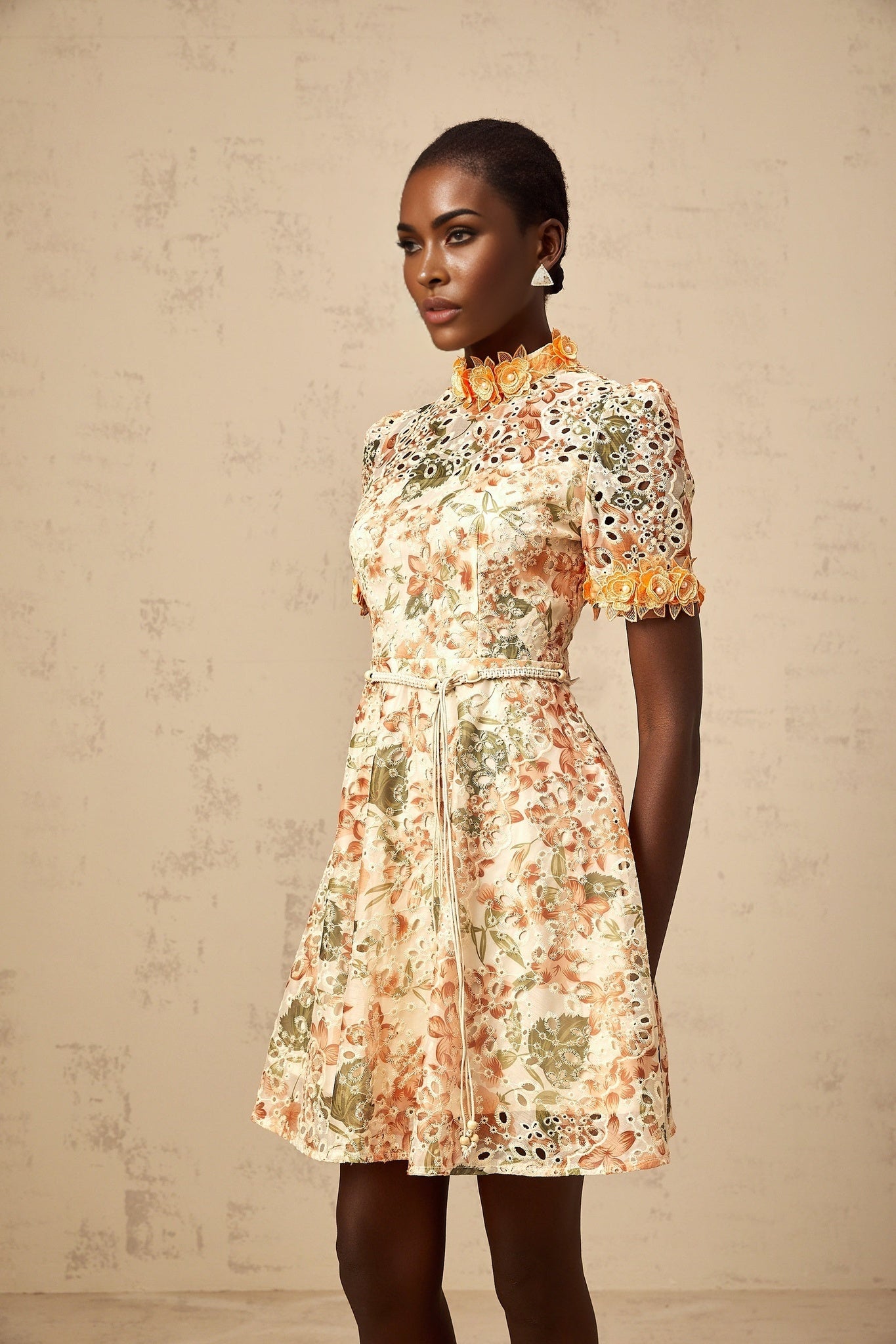 A vibrant orange mini dress with delicate flower embroidery and embellishments adorning the fabric creating a playful and feminine look