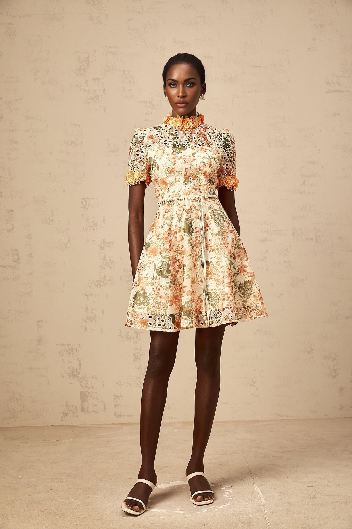 A vibrant orange mini dress with delicate flower embroidery and embellishments decorating the fabric showcasing a feminine and playful design
