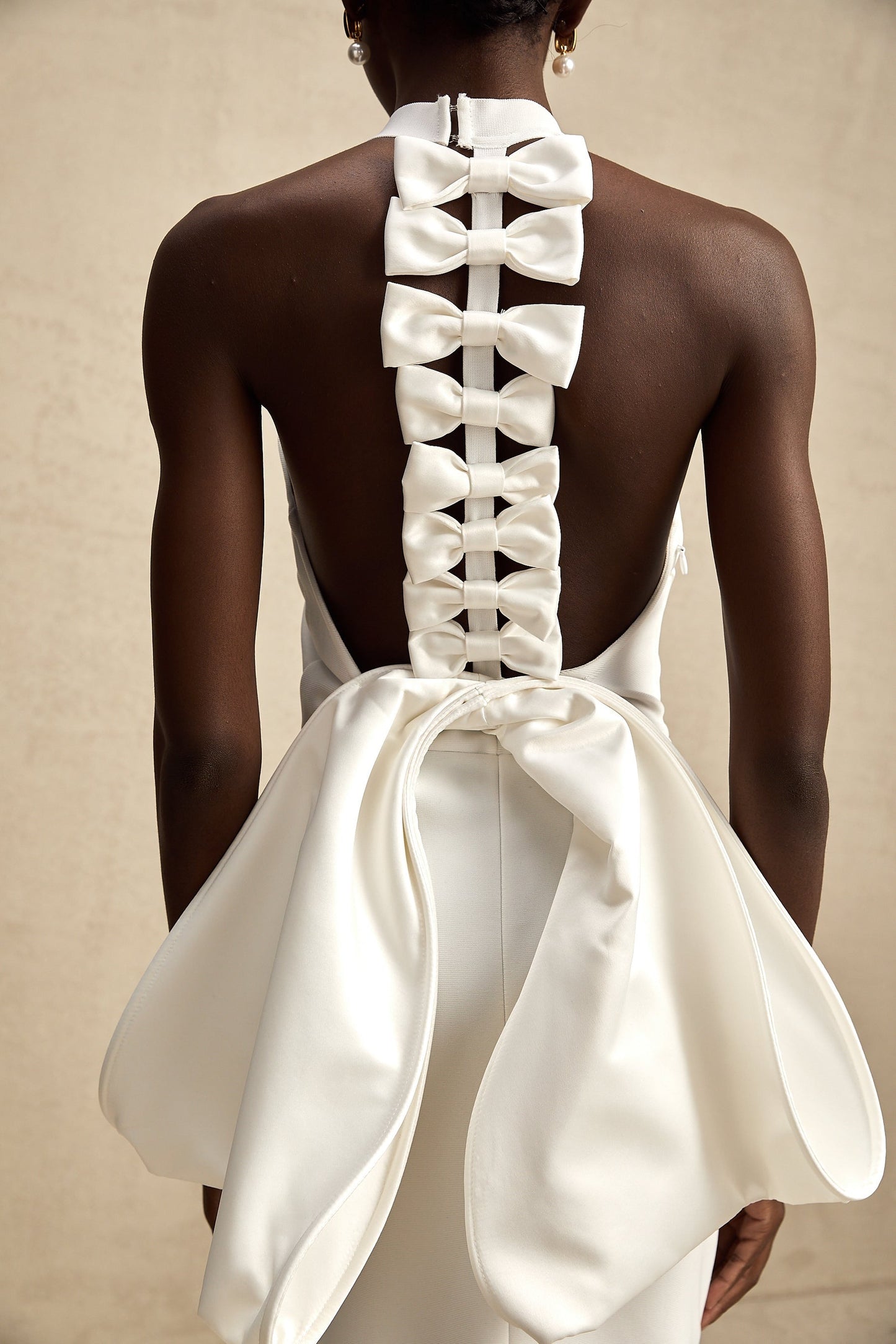 A white bandage dress with an oversized bow accent named Capucine featuring a formfitting silhouette and elegant design