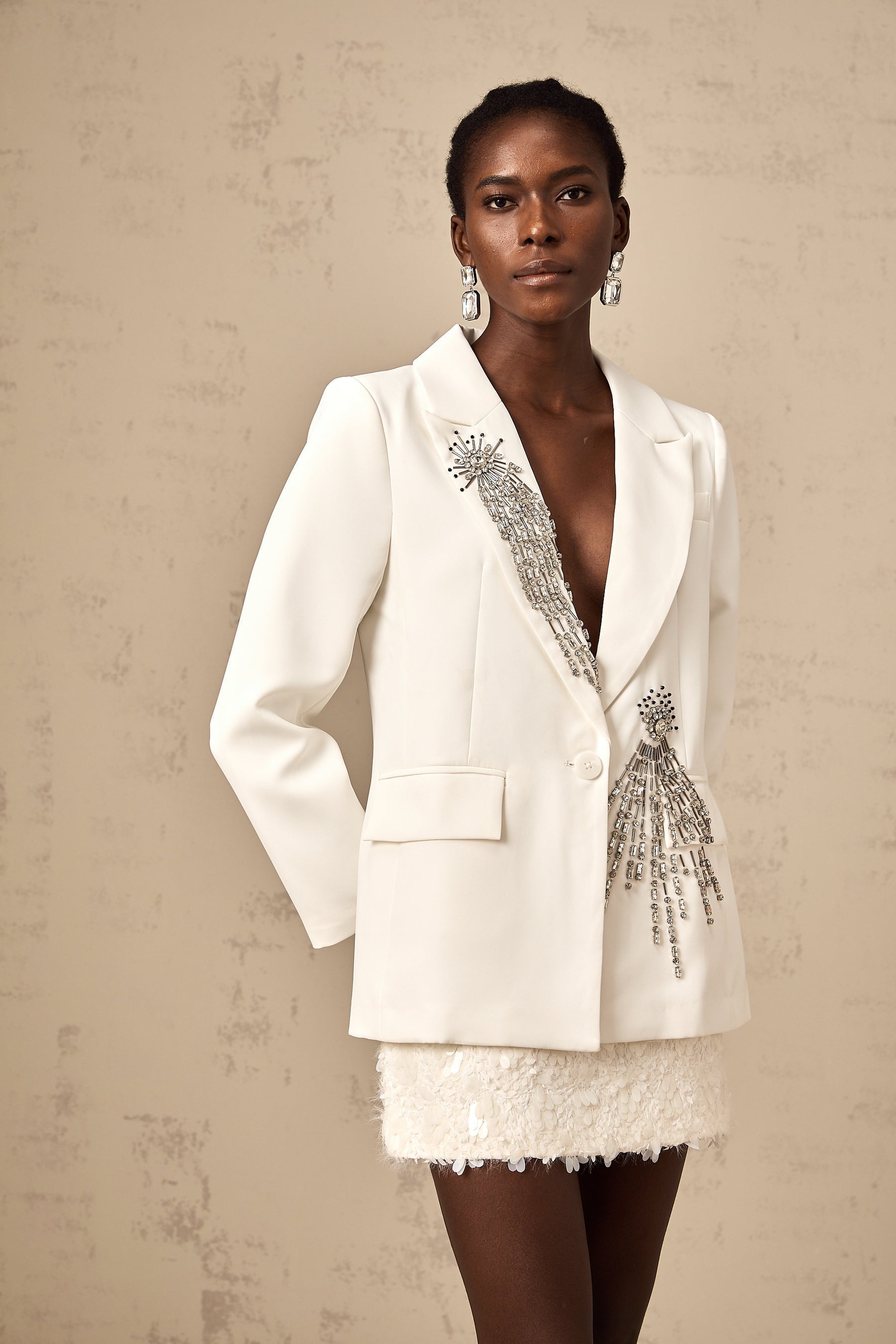 A white blazer adorned with crystal embellishments featuring a tailored fit and sparkly details