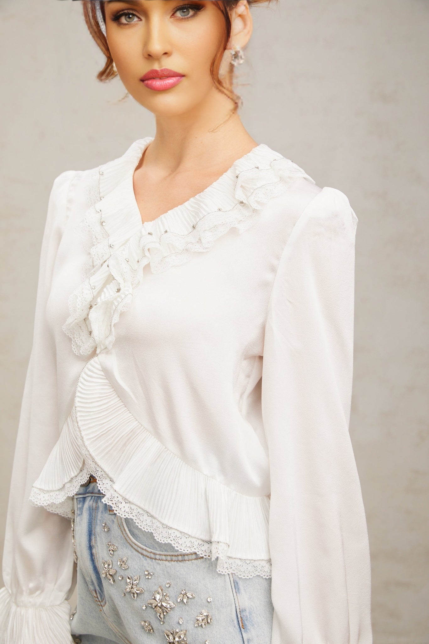 A white buttonup shirt with lace trim and ruffled details