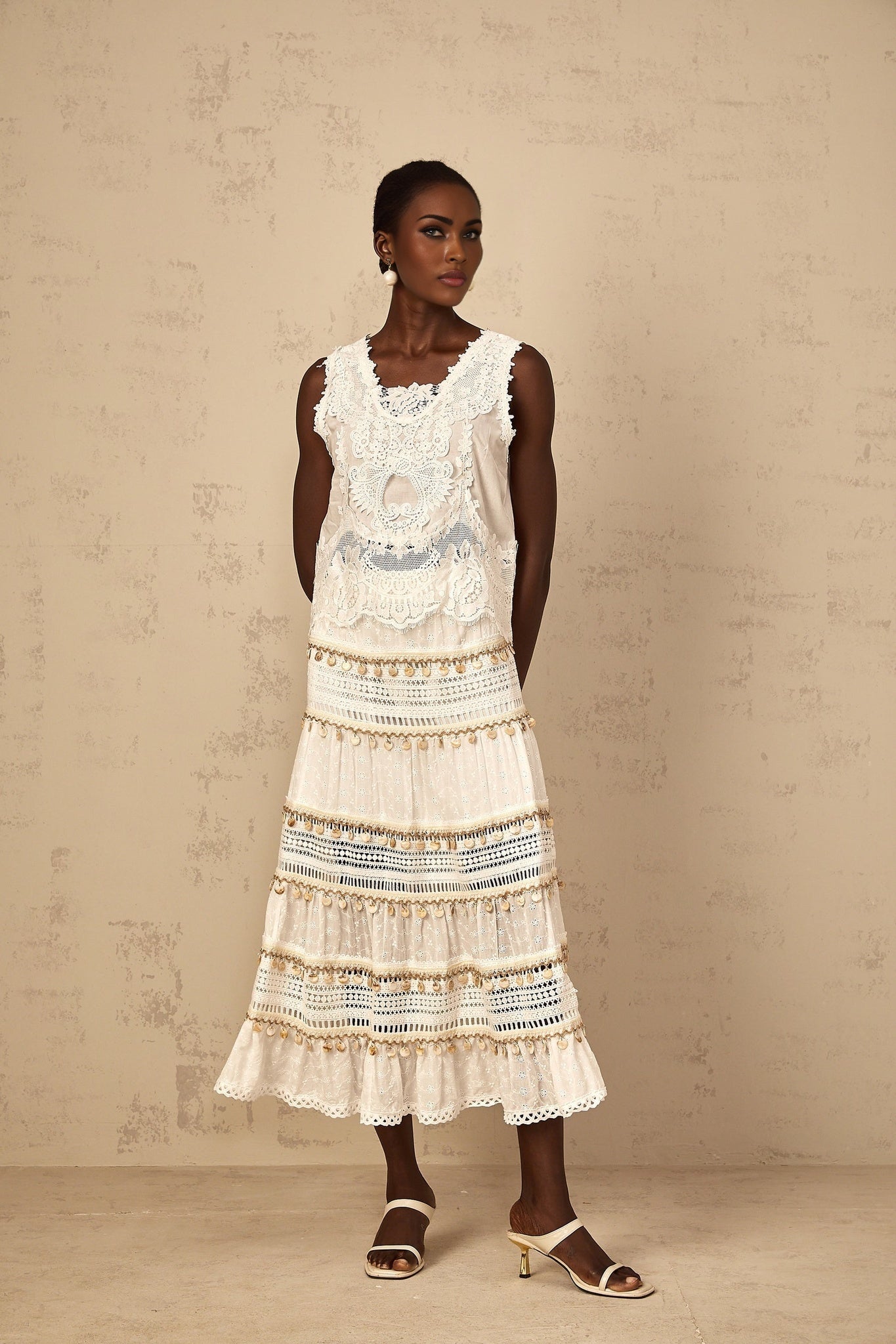 A white cropped tank top with delicate floral embroidery featuring a sleeveless design and a scoop neckline