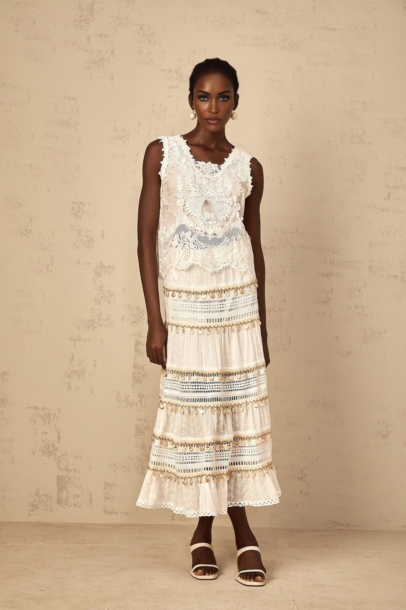 A white cropped tank top with delicate floral embroidery featuring a sleeveless design and a scoop neckline