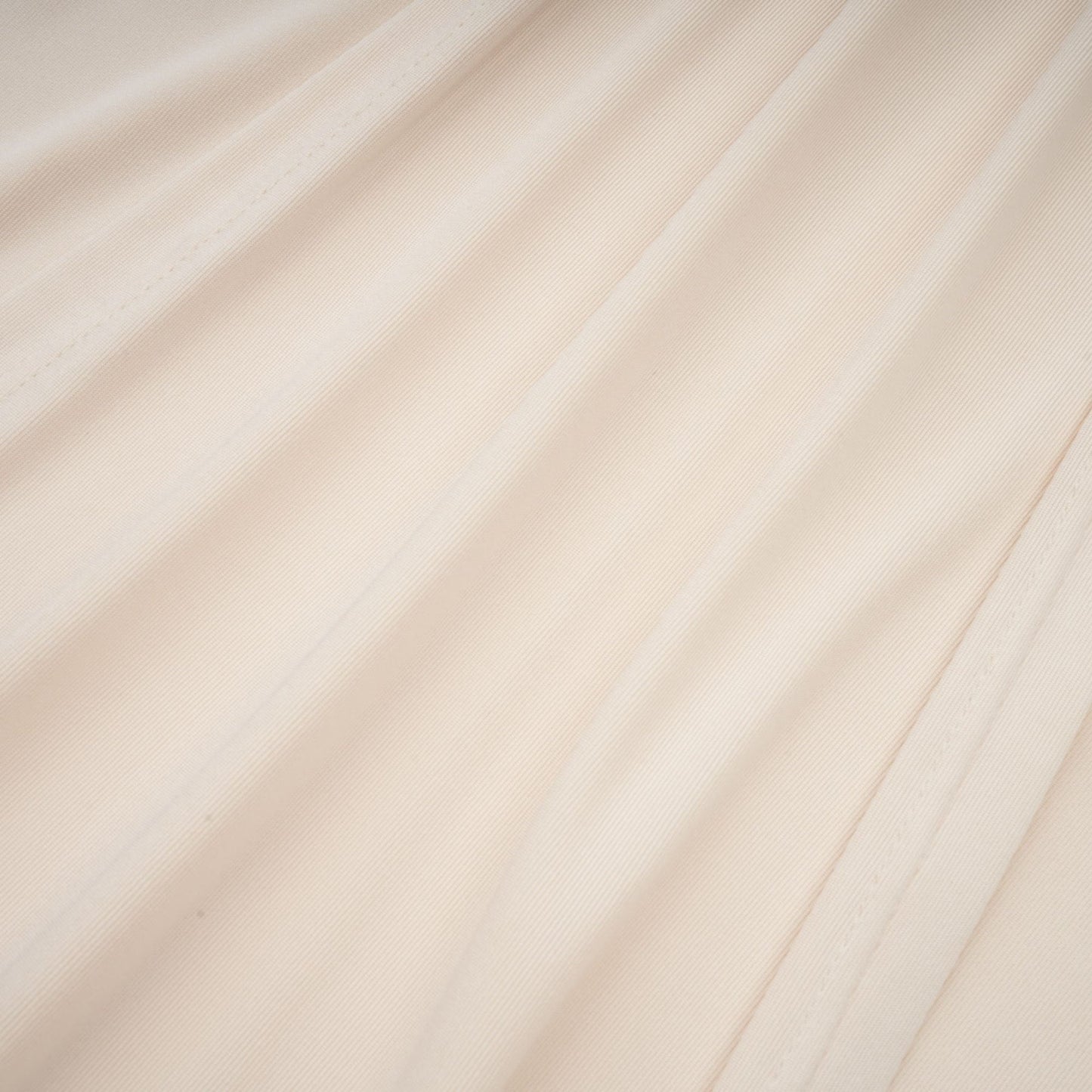 A white floorlength maxi dress with a deep V neckline and draped fabric worn by a model against a plain background