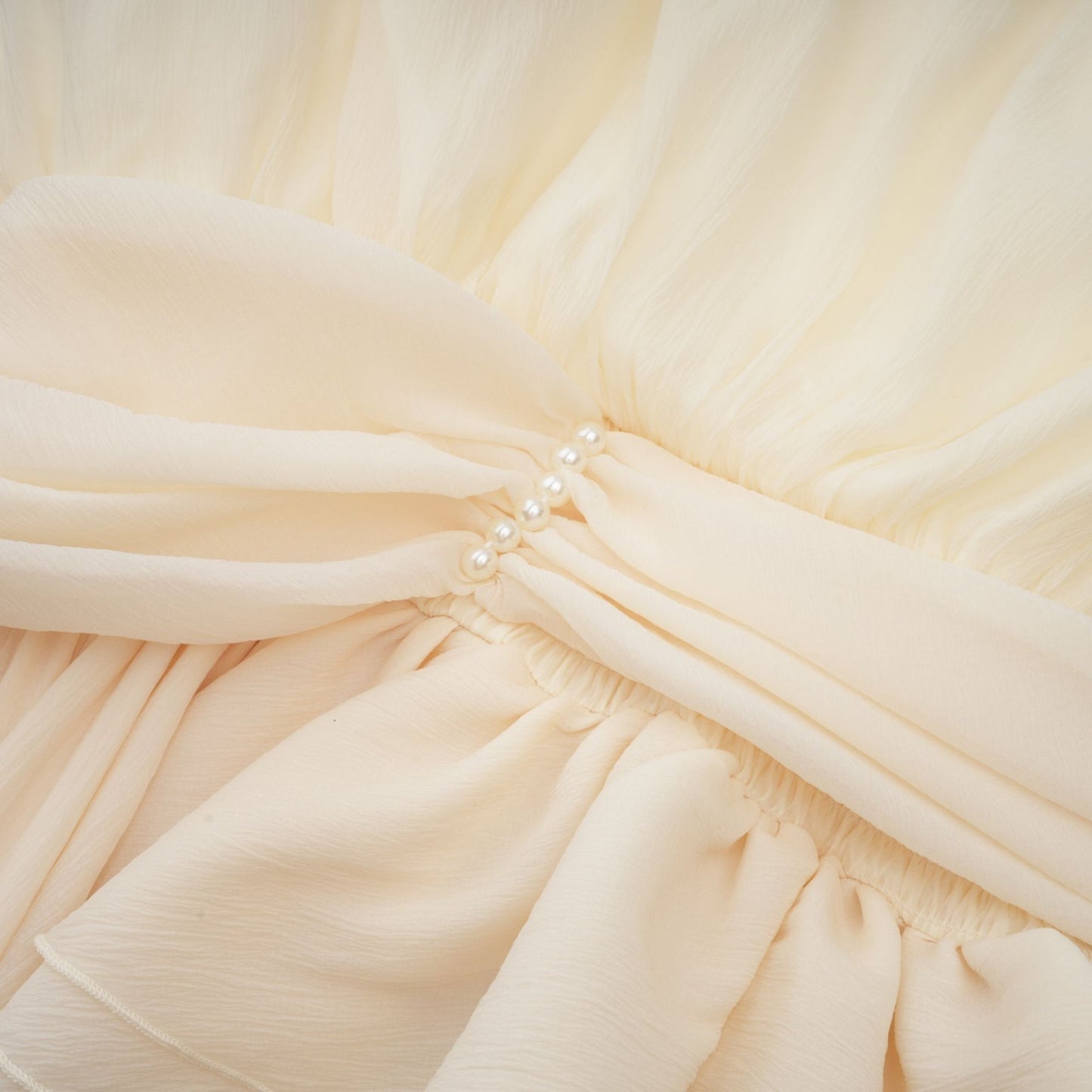 A white halterneck mini dress adorned with faux pearls featuring a sleek silhouette and elegant design