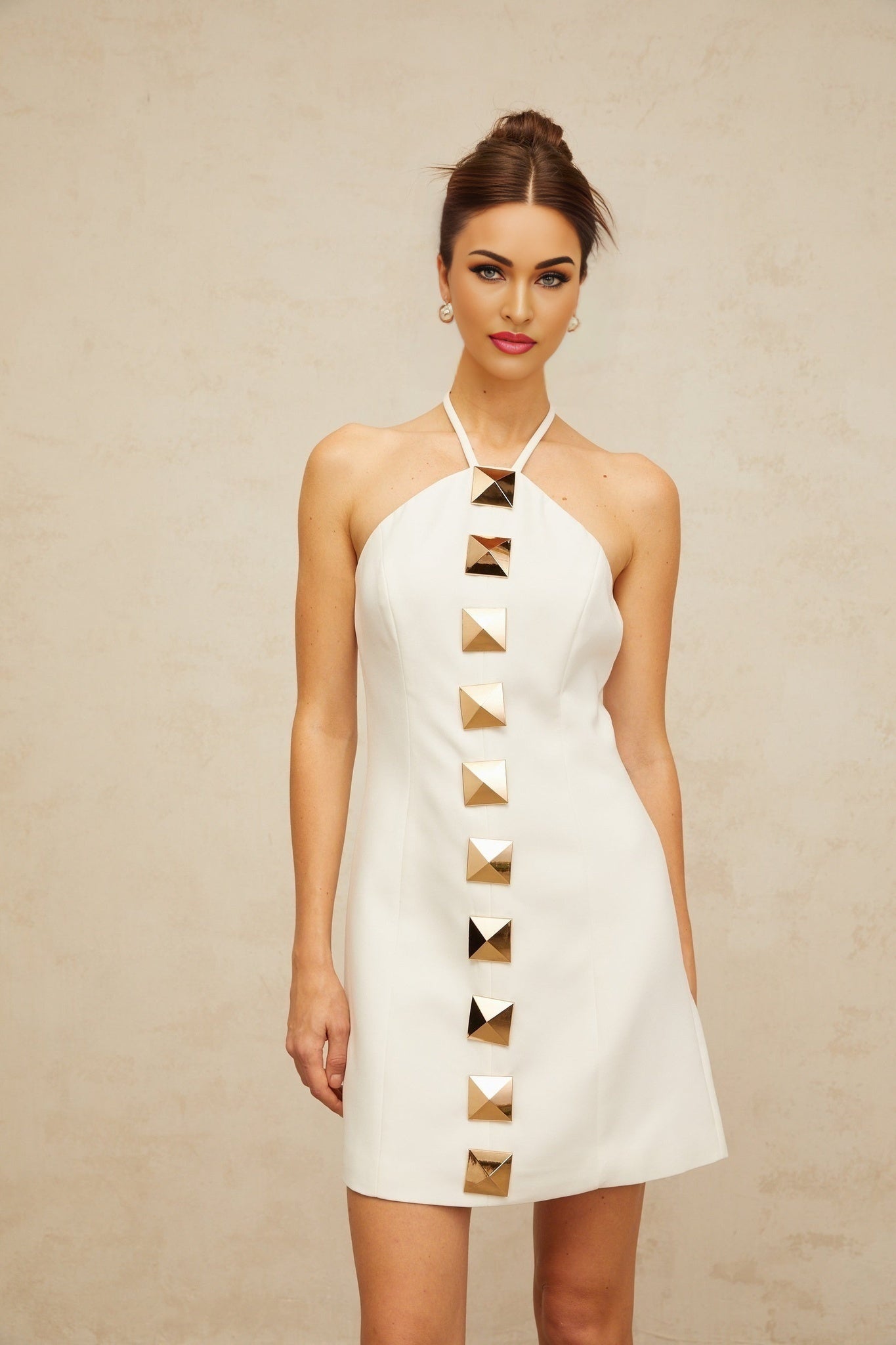 A white halterneck mini dress with an Aline silhouette named Annabelle shown on a model against a plain background