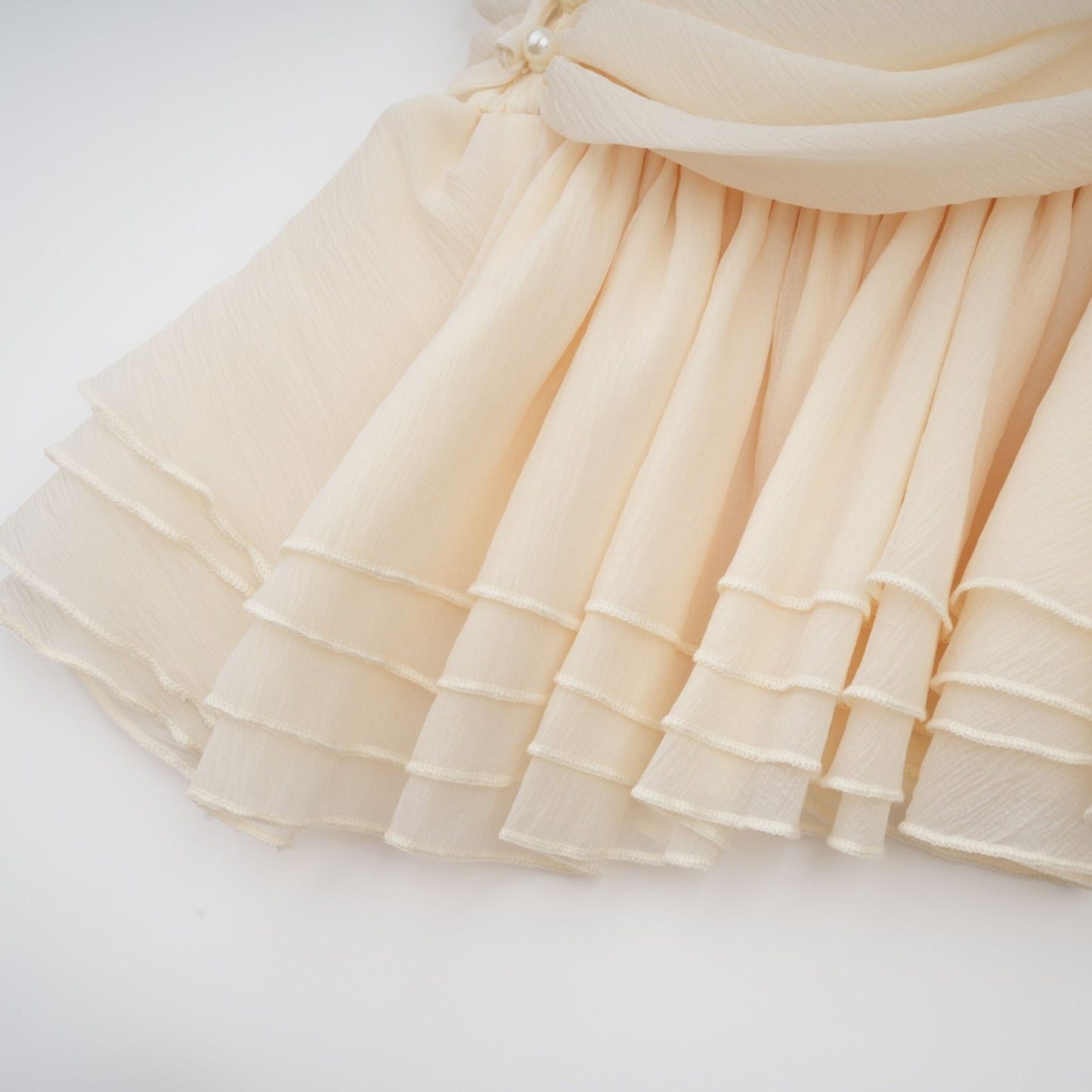 A white halterneck mini dress with faux pearl embellishments on a female model