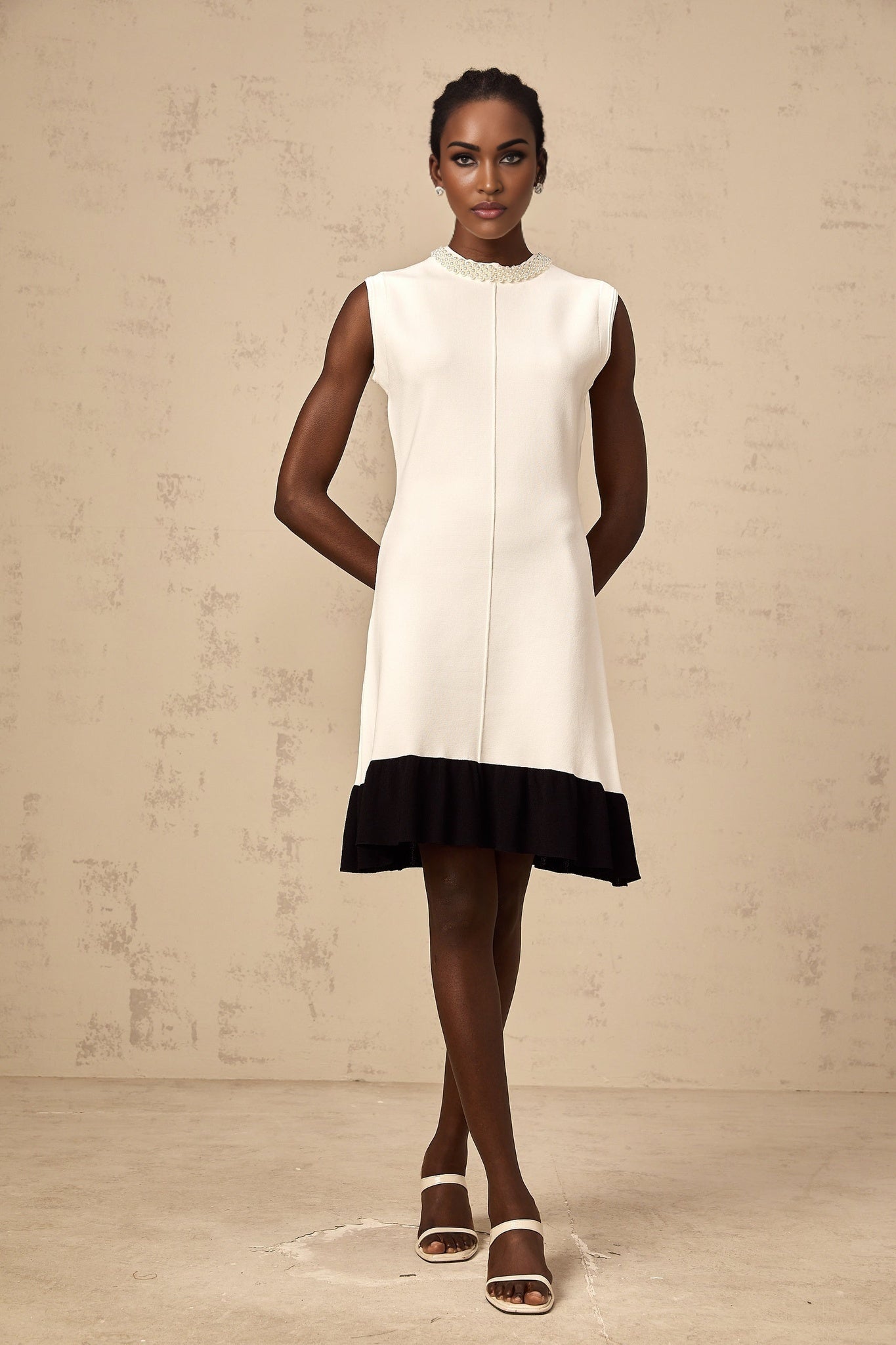 A white knitted cardigan adorned with faux pearl embellishments featuring a classic button front design