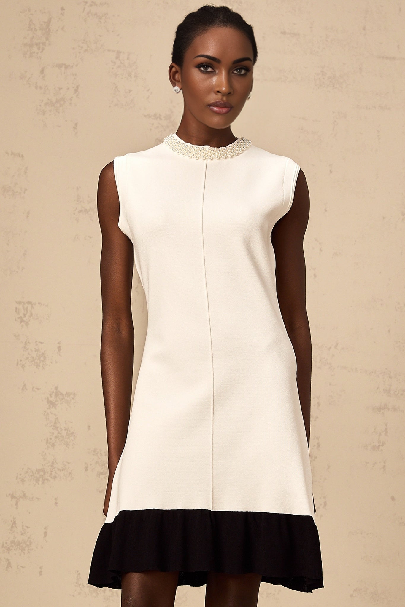 A white knitted cardigan adorned with faux pearl embellishments featuring a classic design and button front closure