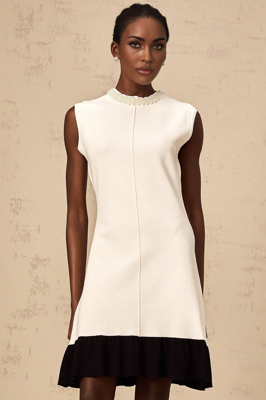 A white knitted cardigan adorned with faux pearl embellishments featuring a classic design and button front closure