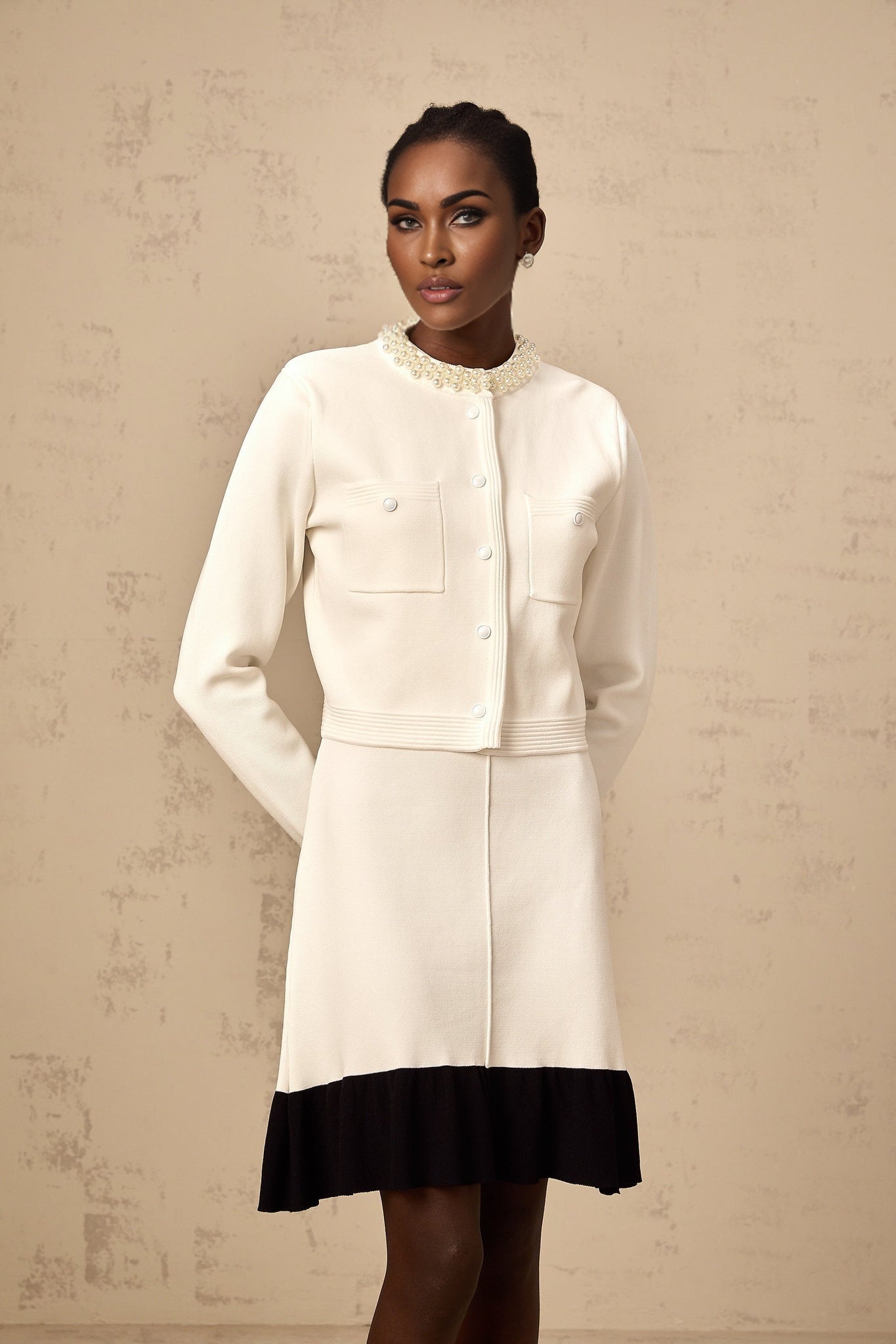 A white knitted cardigan adorned with faux pearl embellishments