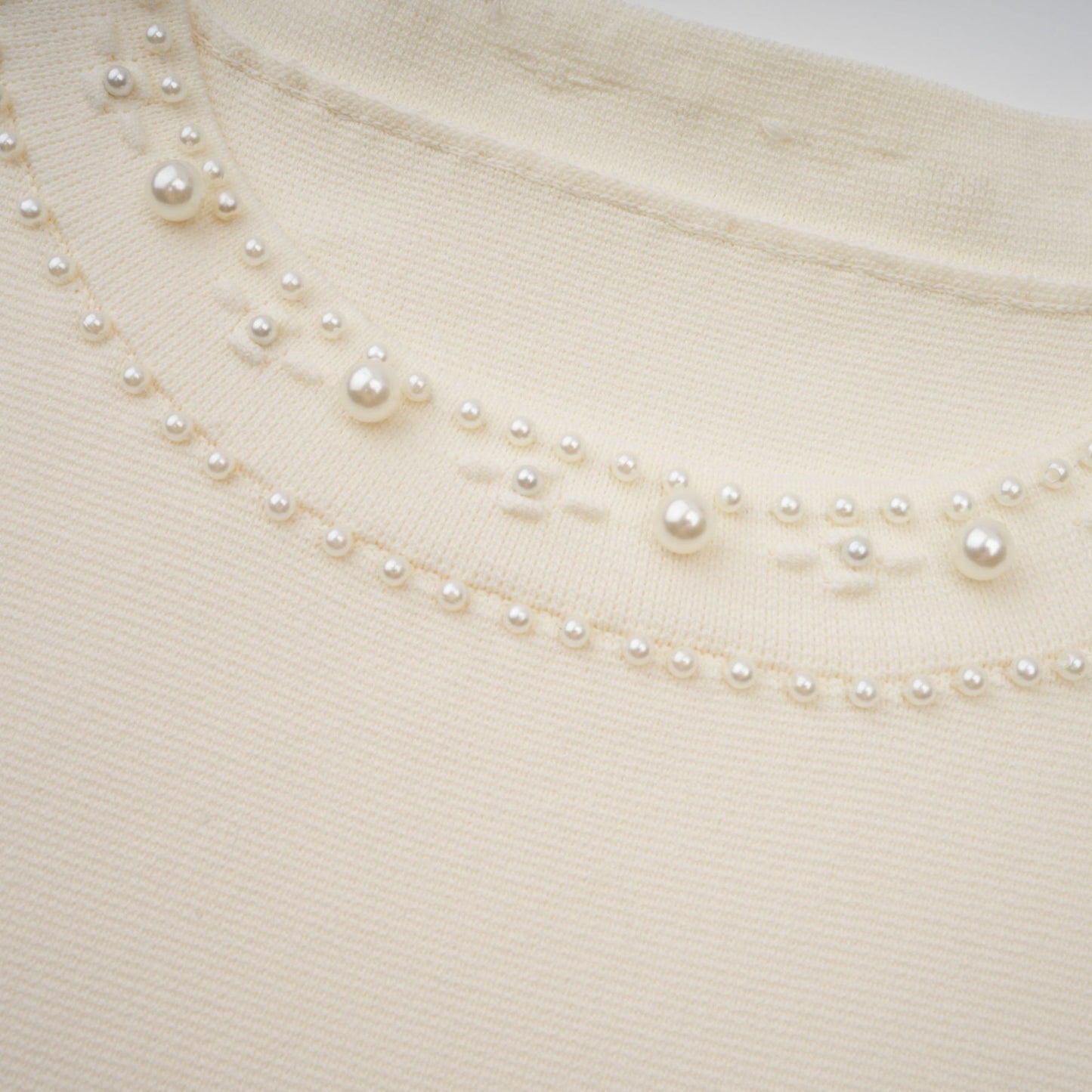 A white knitted maxi dress with faux pearl embellishments by Donatienne
