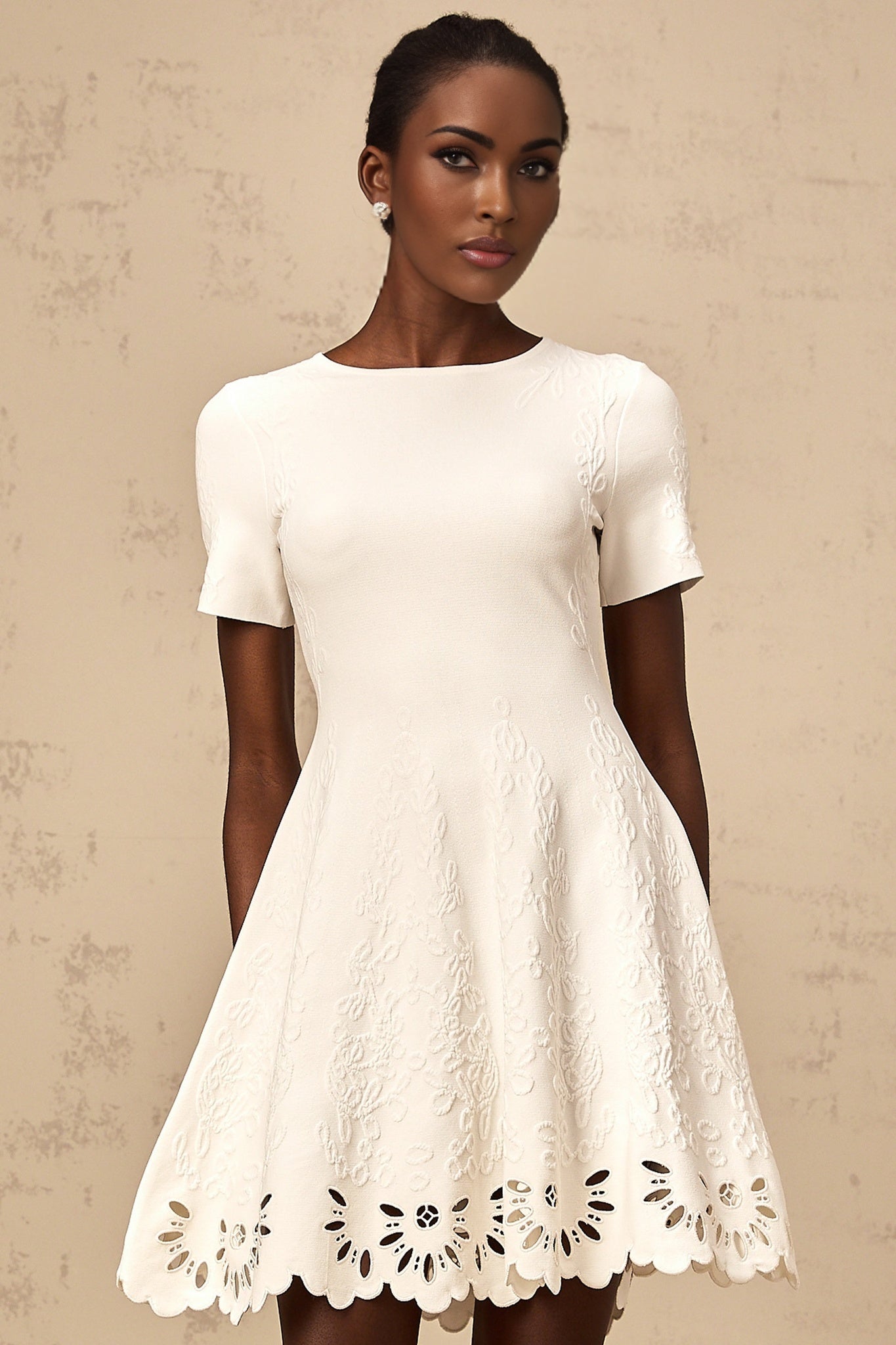 A white knitted mini dress with cut out jacquard pattern details and a short hemline