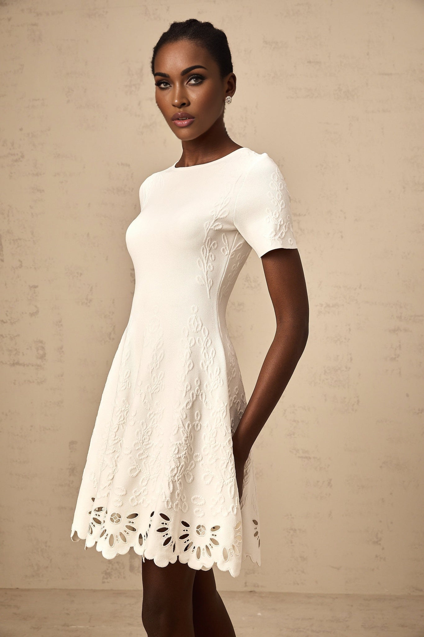 A white knitted mini dress with cut out jacquard patterns named Emilie featuring a short length and textured design