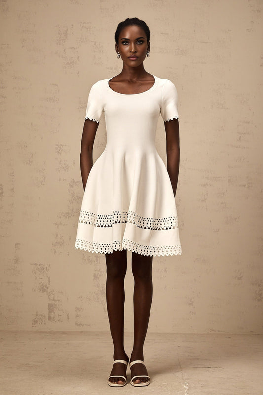 A white knitted mini dress with cutout details featuring a fleur design pattern
