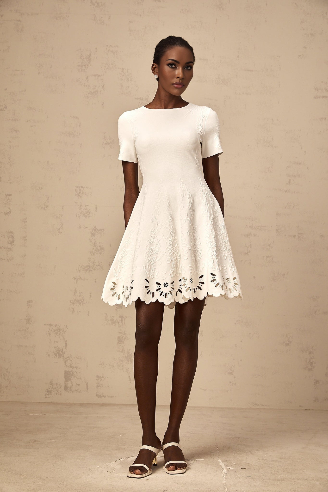 A white knitted mini dress with jacquard pattern and cut out details worn by a model named Emilie