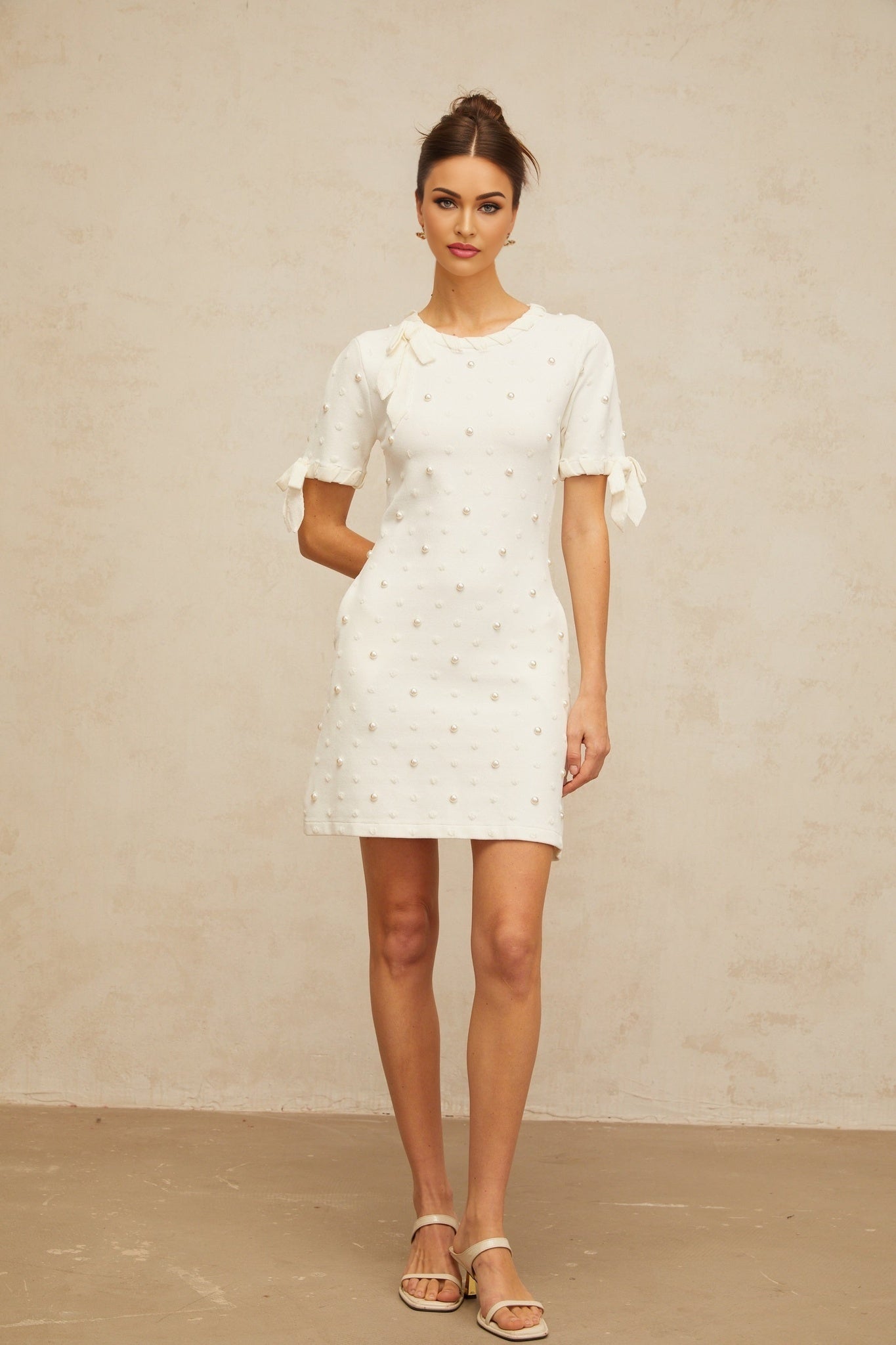 A white knitted mini dress with small polka dots and a heart pattern featuring short sleeves and a fitted silhouette called Prunelle