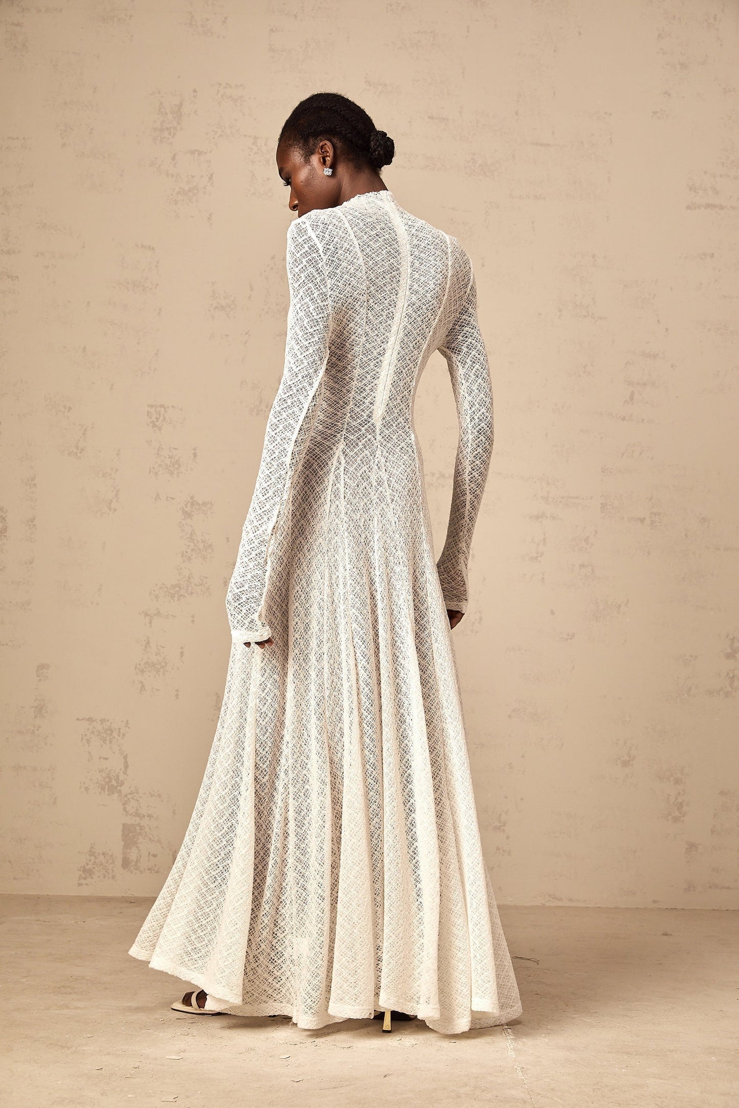 A white lace maxi dress with a wavy pattern featuring a long flowing design and intricate lace details throughout