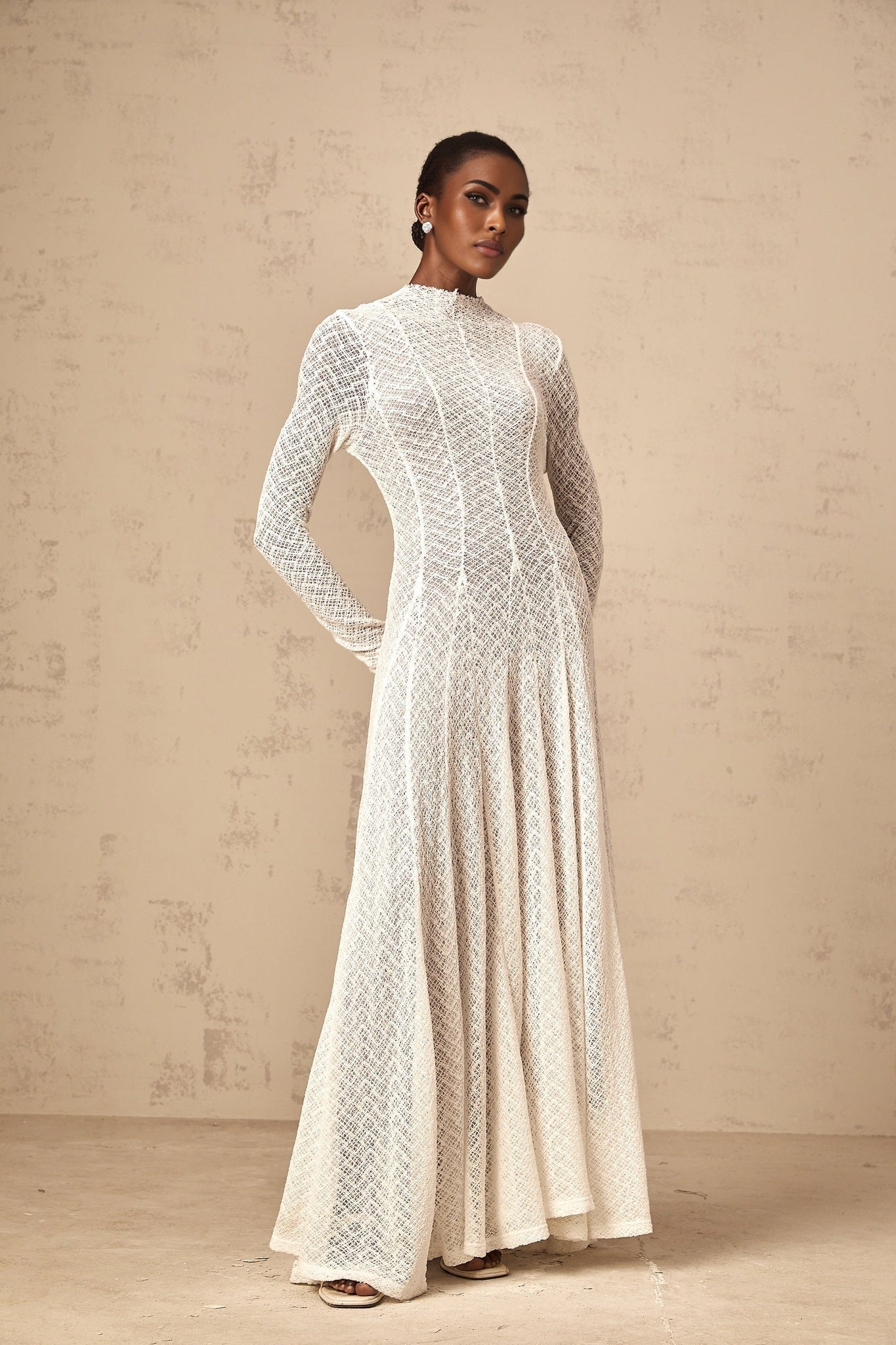 A white lace maxi dress with a wavy pattern featuring a long flowing skirt and delicate lace details throughout