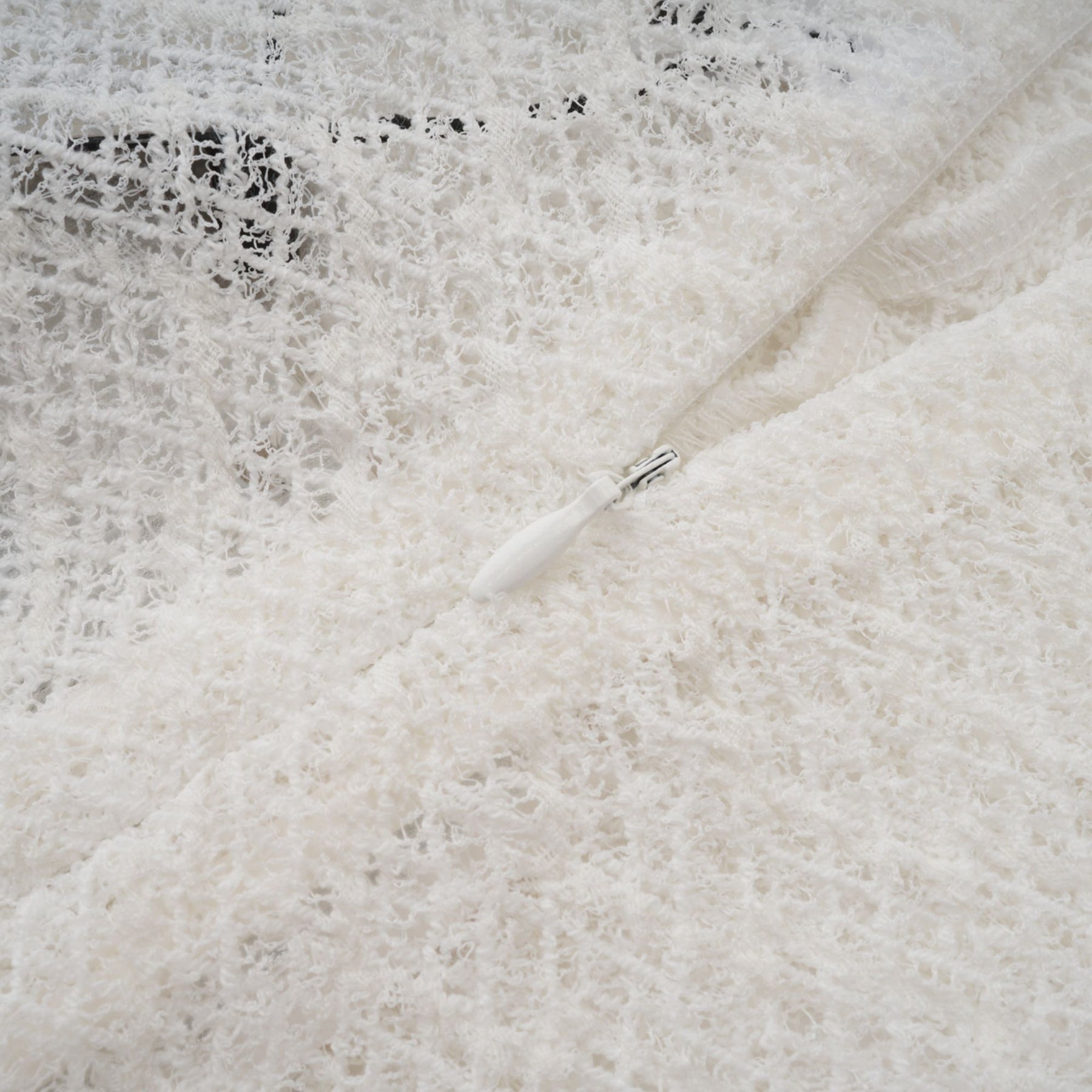 A white lace maxi dress with a wavy pattern worn by a model standing in a neutral backdrop