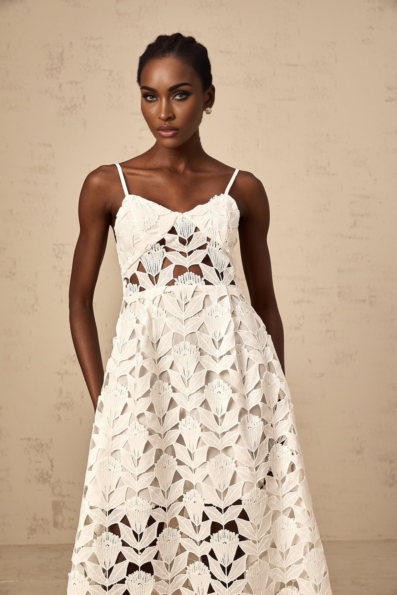 A white lace midi dress with cutout details featuring a delicate floral pattern and a fitted silhouette