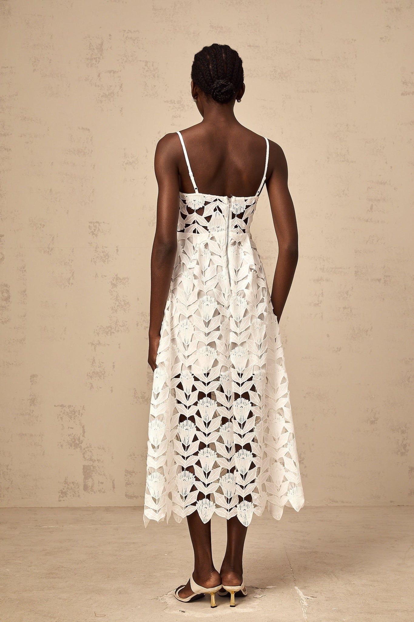 A white lace midi dress with cutout details featuring a delicate floral pattern and a fitted silhouette