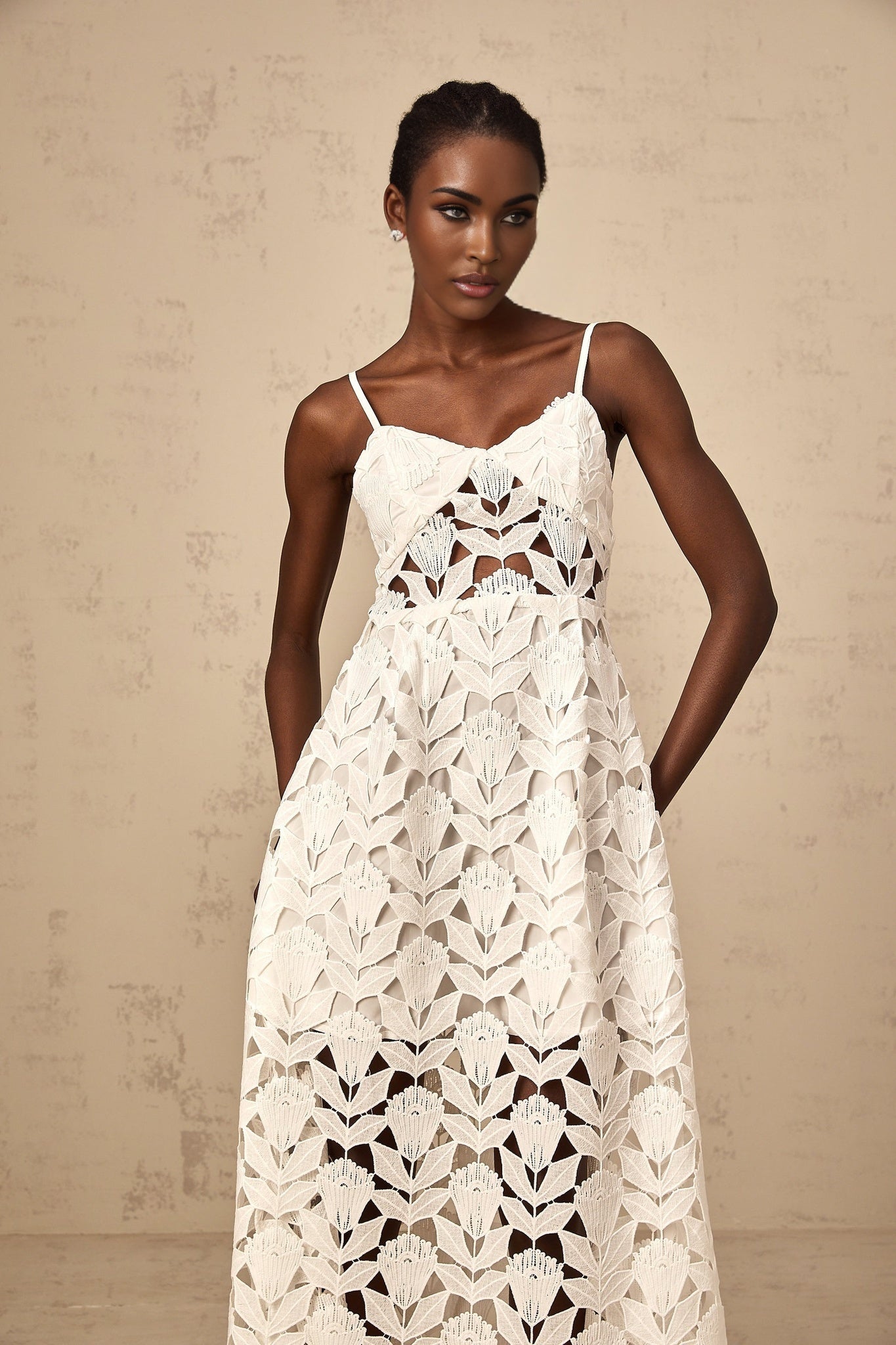 A white lace midi dress with cutout details featuring a delicate floral pattern and a fitted silhouette