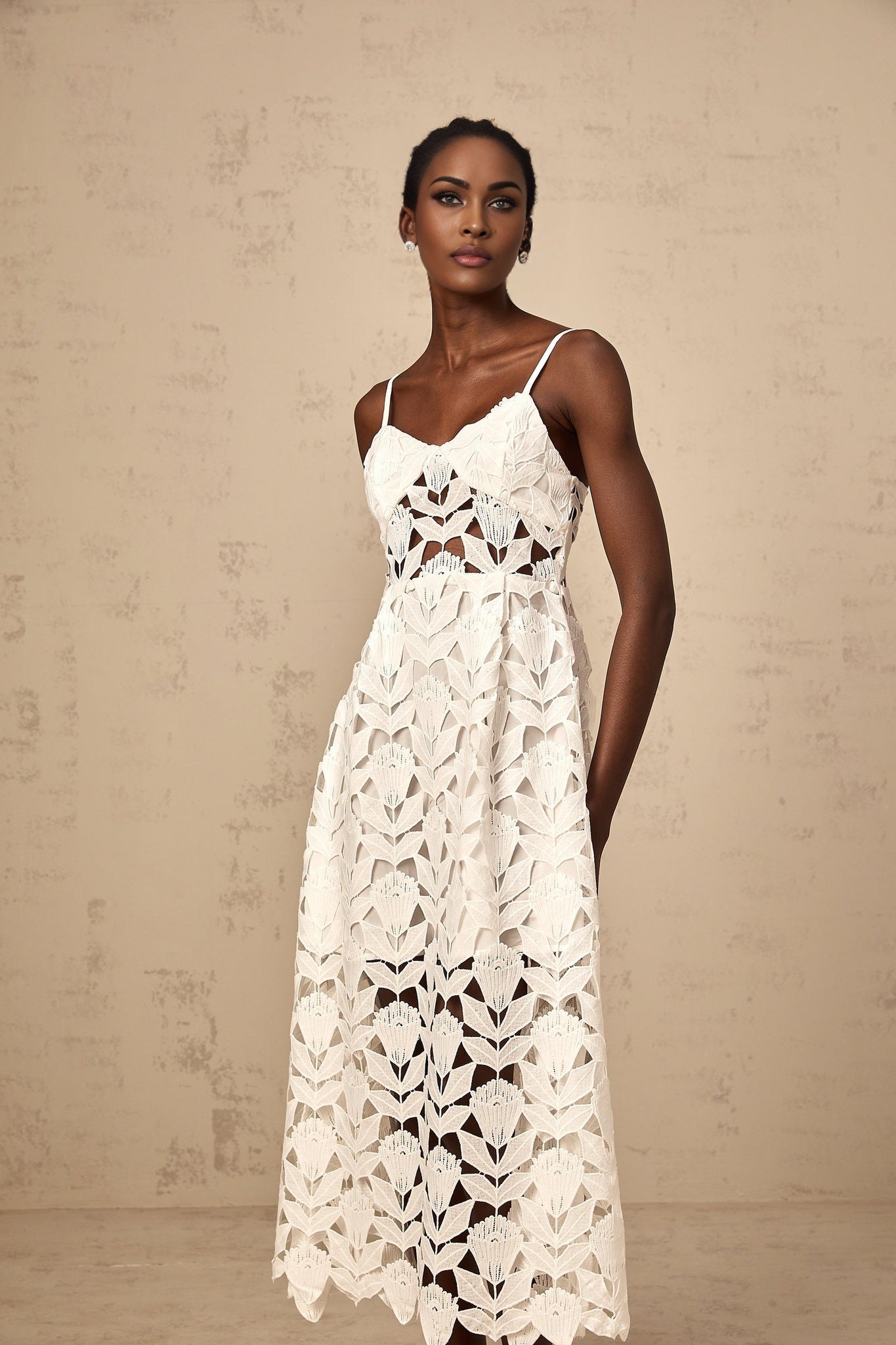 A white lace midi dress with cutout details featuring a delicate floral pattern and feminine silhouette